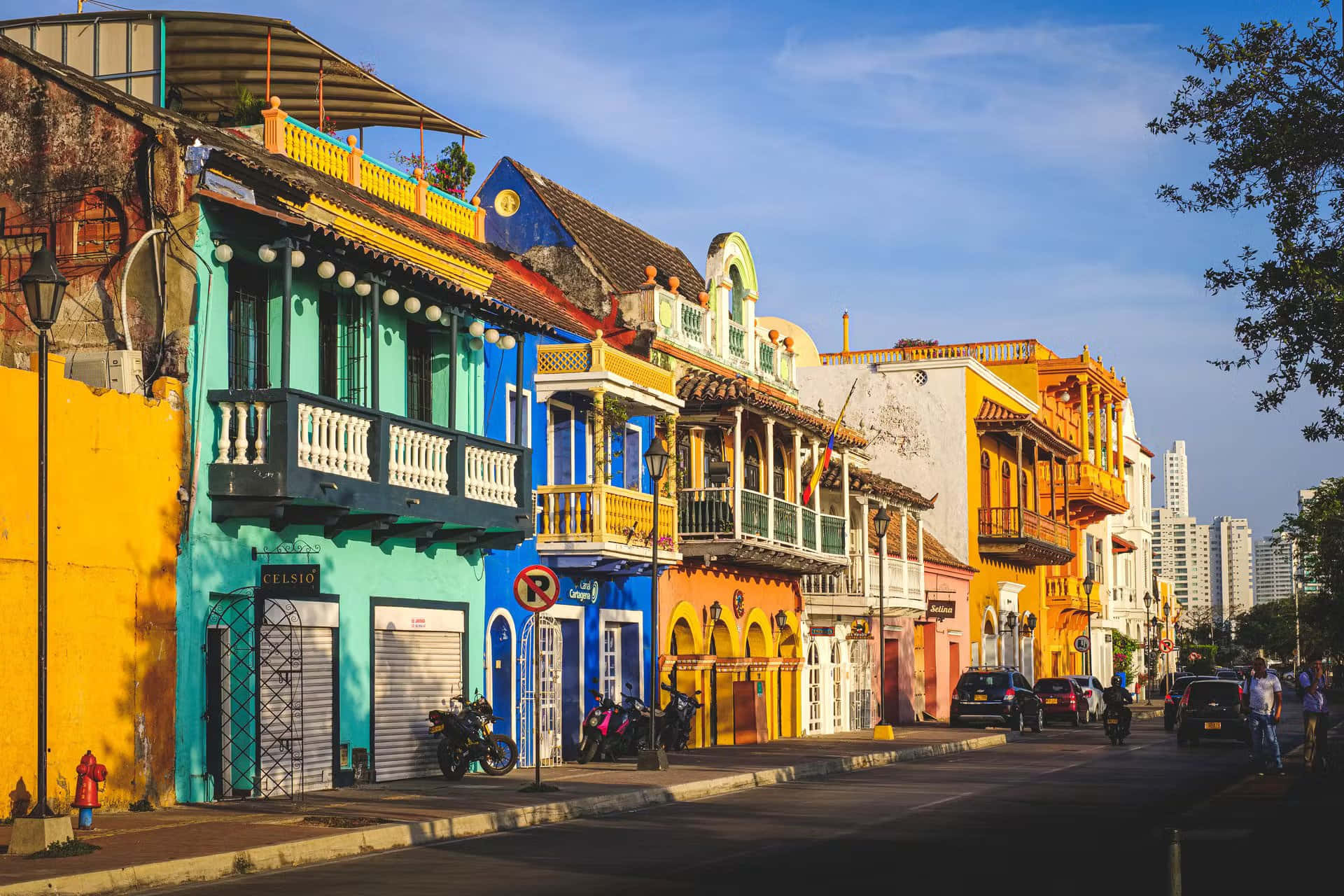 Colombia 桌布 壁紙 — 充滿活力的殖民時期建築，帶有陽台，排列在一條陽光普照的街道上，構成繁華的城市景觀。