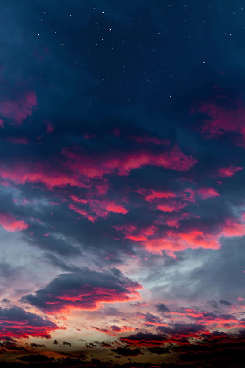 Clouds Aesthetics 桌布 壁紙 — 充滿活力的洋紅色和深紅色雲彩在暮色天空中劃過，天空點綴著閃爍的星星，下方是黑暗的地平線。