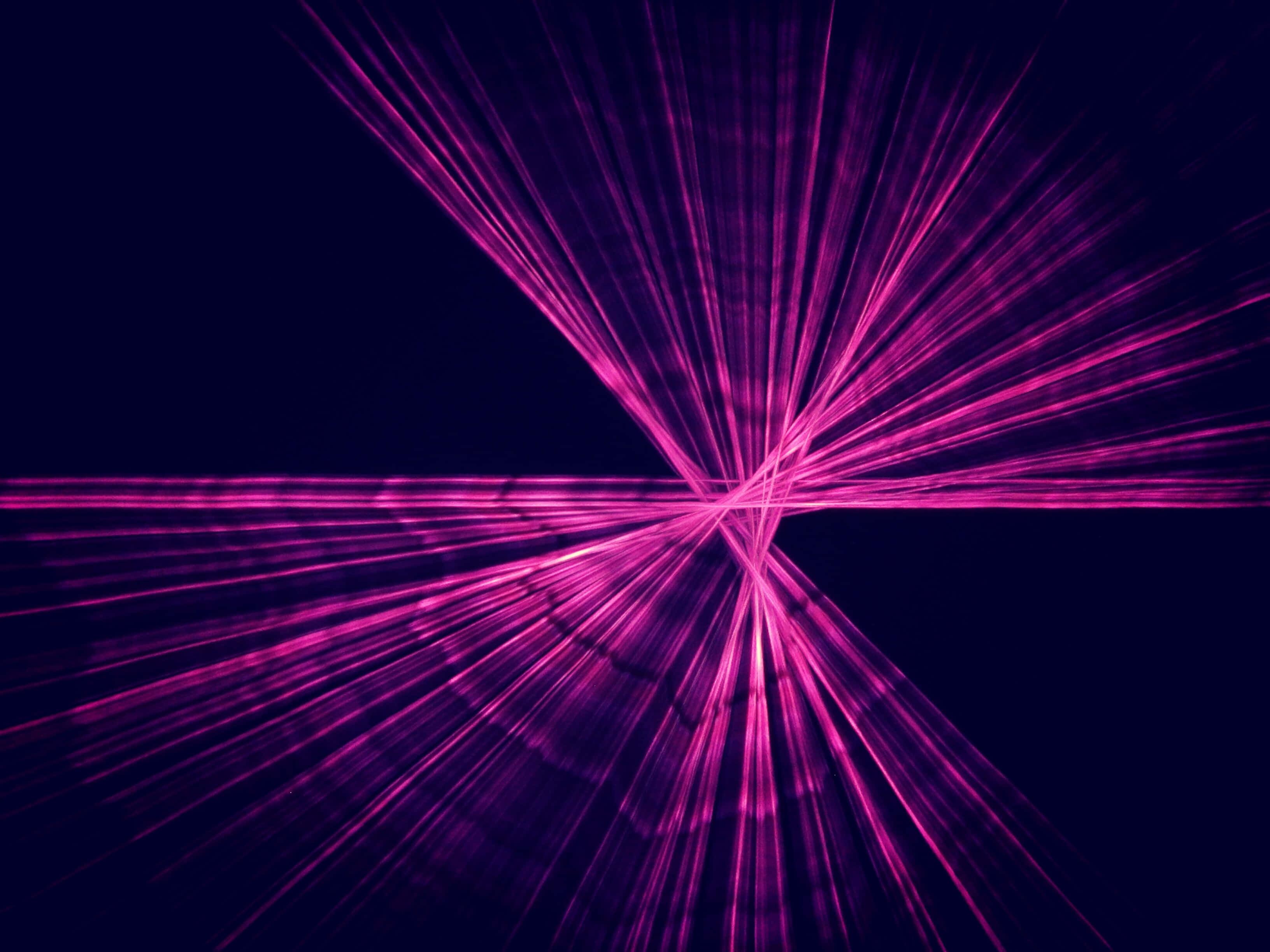 Laser 桌布 壁紙 — 充滿活力的洋紅色雷射光束從中央交叉點向外輻射，背景為深海軍藍色。