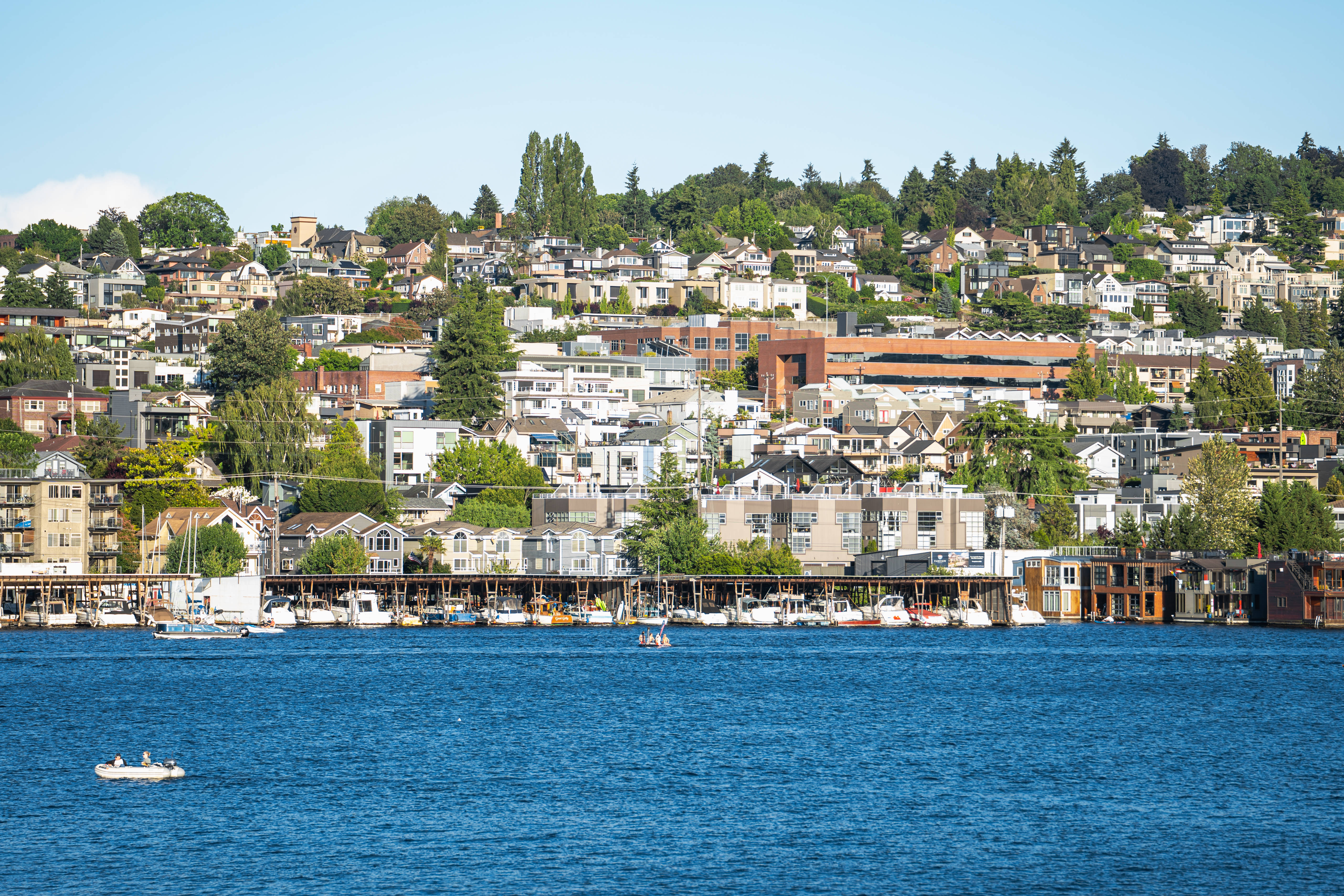 seattle 4K 桌布 壁紙 — 充滿活力的海濱城市景觀，樹木繁茂的山丘上密集排列著房屋，俯瞰著深藍色的港灣，港灣中有船隻。
