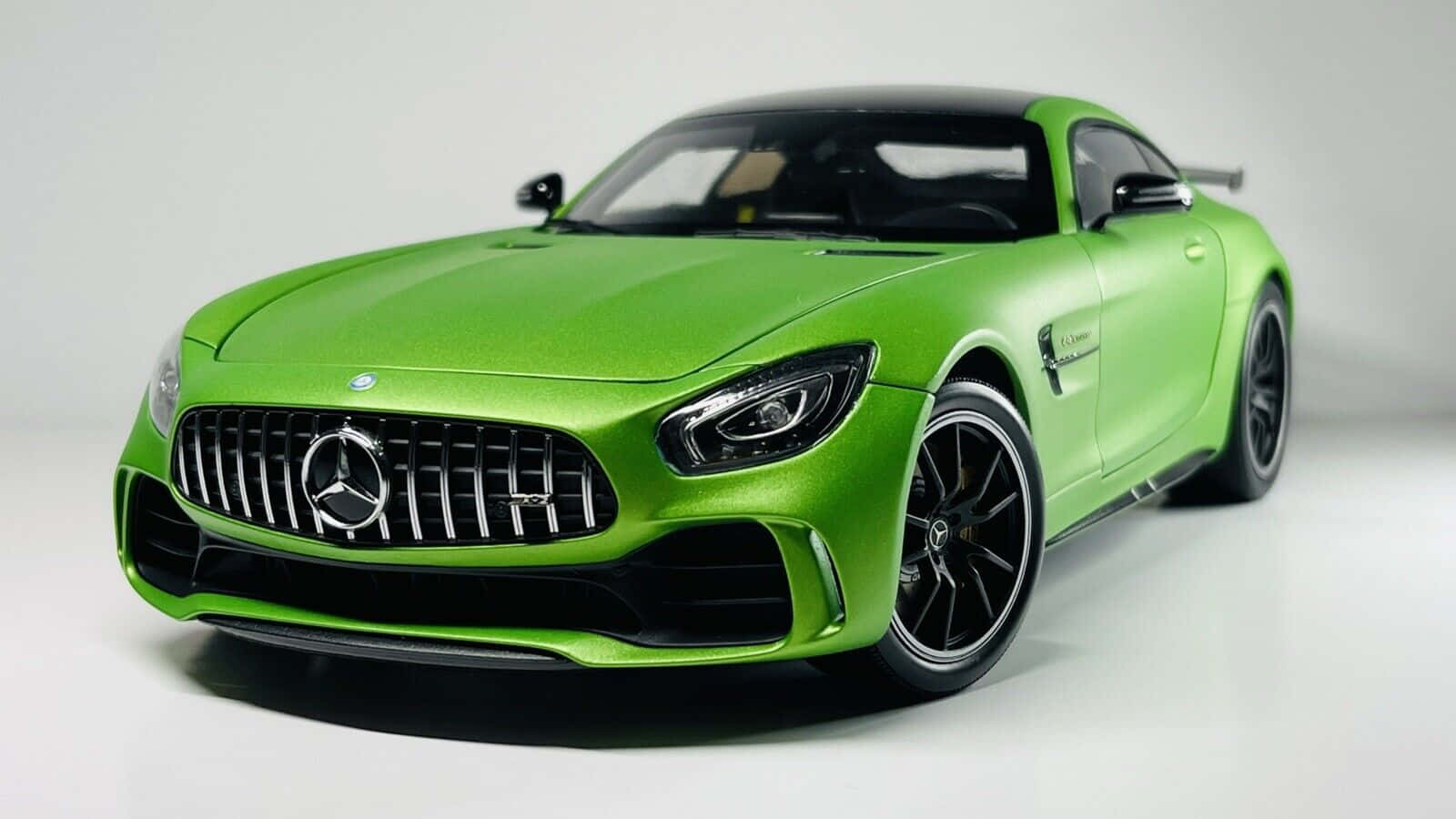 汽車 桌布 壁紙 — 充滿活力的消光綠色 Mercedes-AMG GT 跑車模型，帶有黑色點綴和精細格柵，置於潔白的工作室背景上。