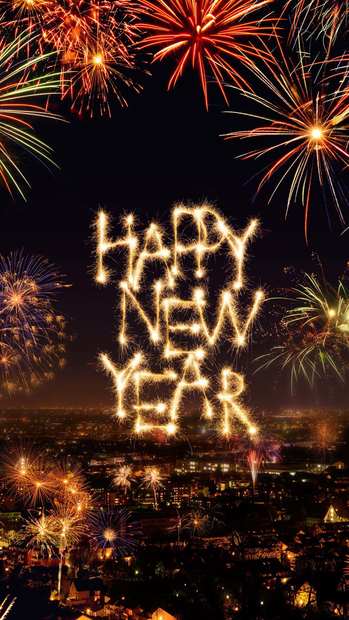 新年 桌布 壁紙 — 充滿活力的煙火在城市景觀上空綻放，閃爍的字母在夜空中拼出「HAPPY NEW YEAR」。