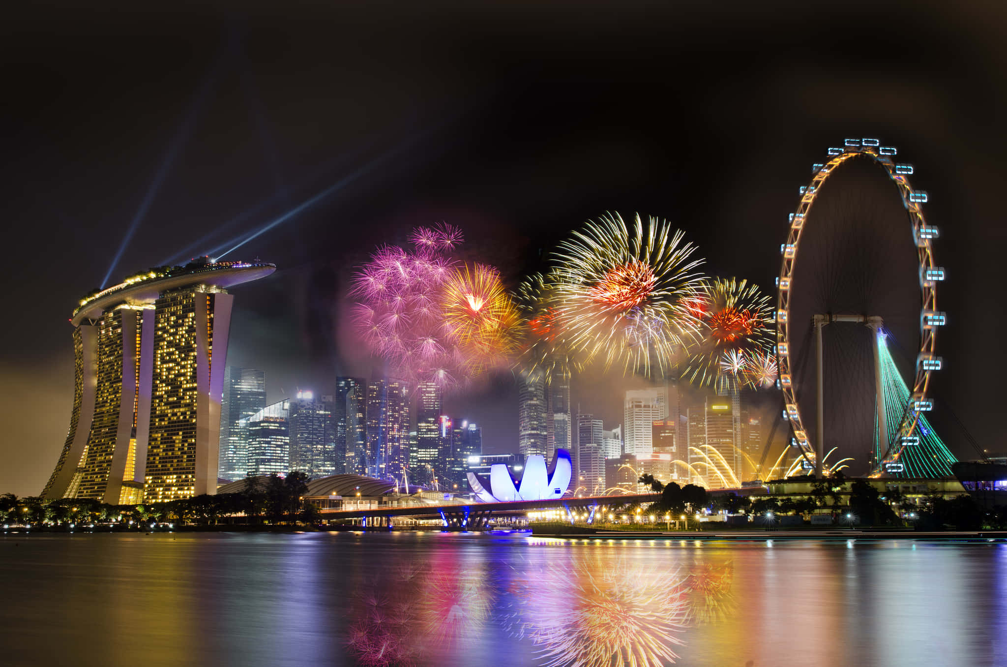 Fireworks 桌布 壁紙 — 充滿活力的煙火在新加坡標誌性的天際線上綻放，夜晚的濱海灣金沙和新加坡摩天輪在下方閃耀。