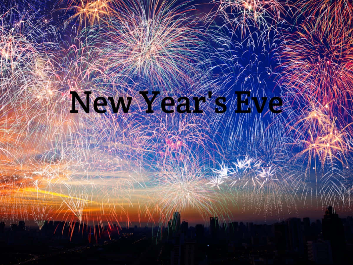 New Years Eve 桌布 壁紙 — 充滿活力的煙火在暮色中的城市天際線上爆炸，慶祝除夕夜。