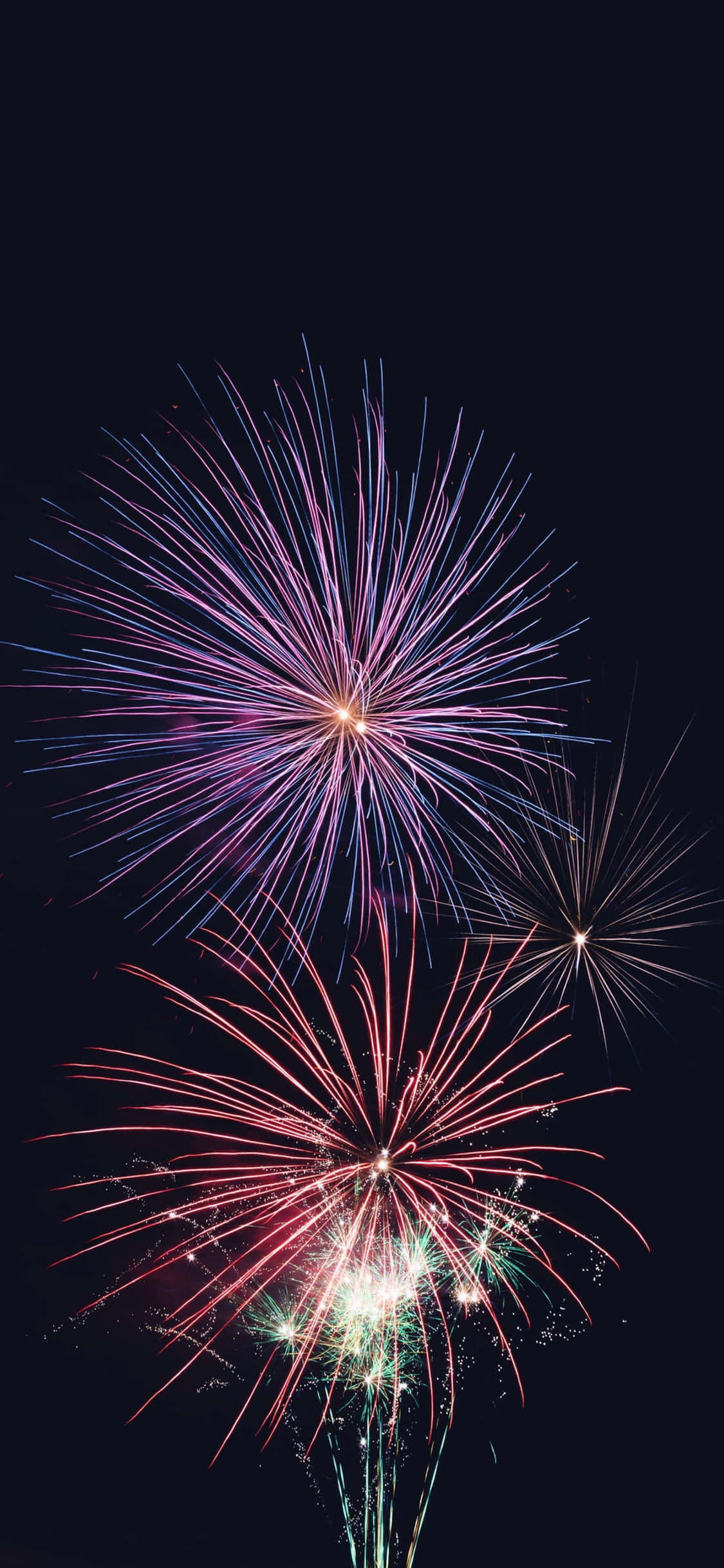 New Year Phone 桌布 壁紙 — 充滿活力的煙火在深黑色的夜空中綻放出紫色、粉紅色和綠色的燦爛爆發。