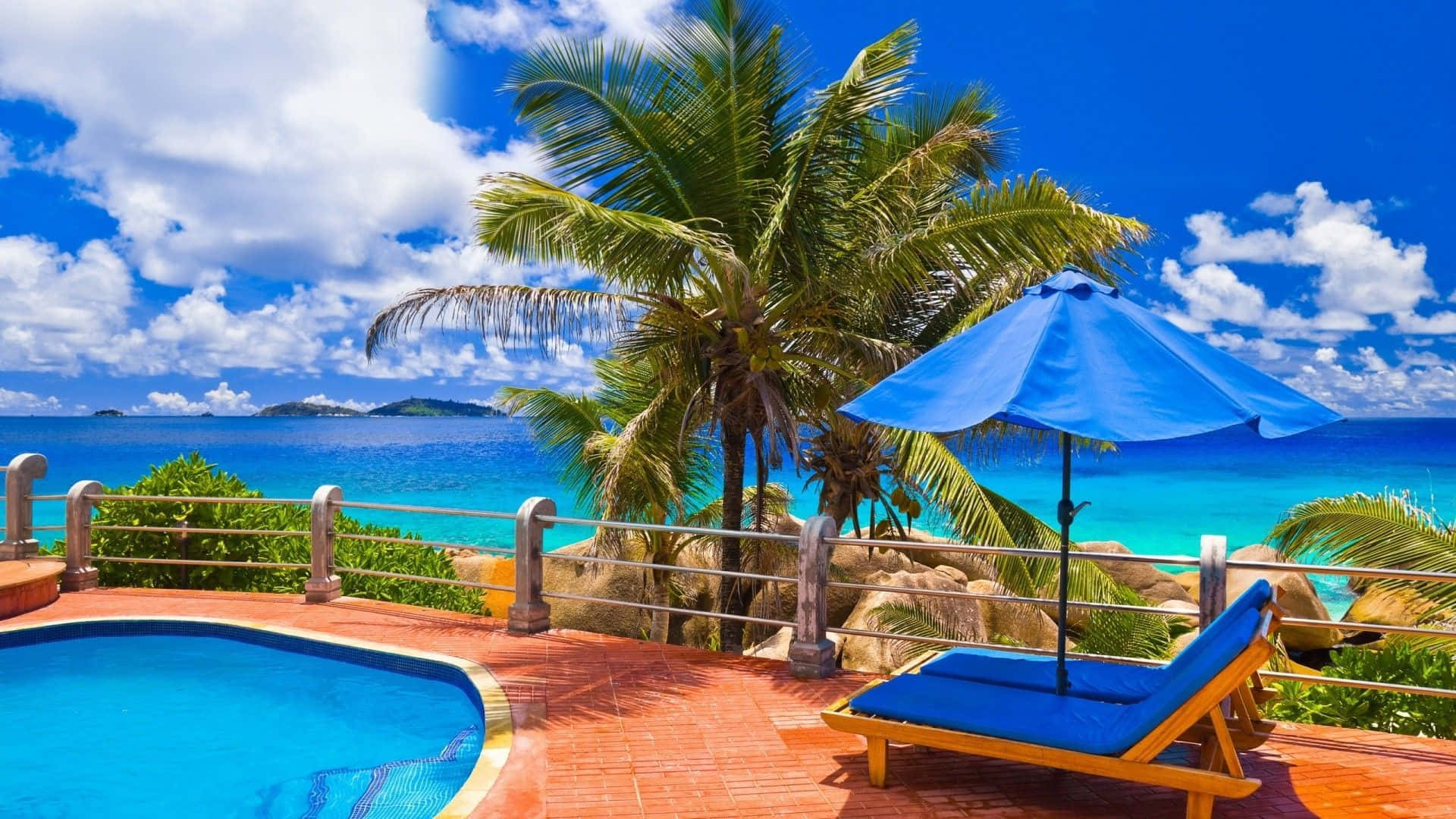 Beach Resort 桌布 壁紙 — 充滿活力的熱帶池畔休息區，設有藍色遮陽傘和躺椅，可俯瞰碧綠的海洋和棕櫚樹，天空晴朗明媚。