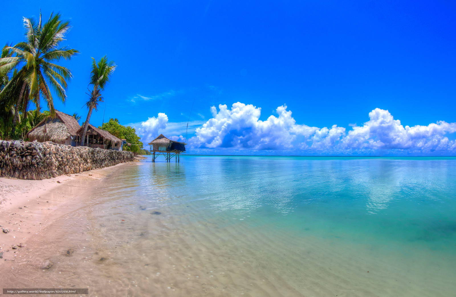 Kiribati 桌布 壁紙 — 充滿活力的熱帶海灘，有碧綠的海水、棕櫚樹和茅草屋，在明亮的藍天下有蓬鬆的白雲。