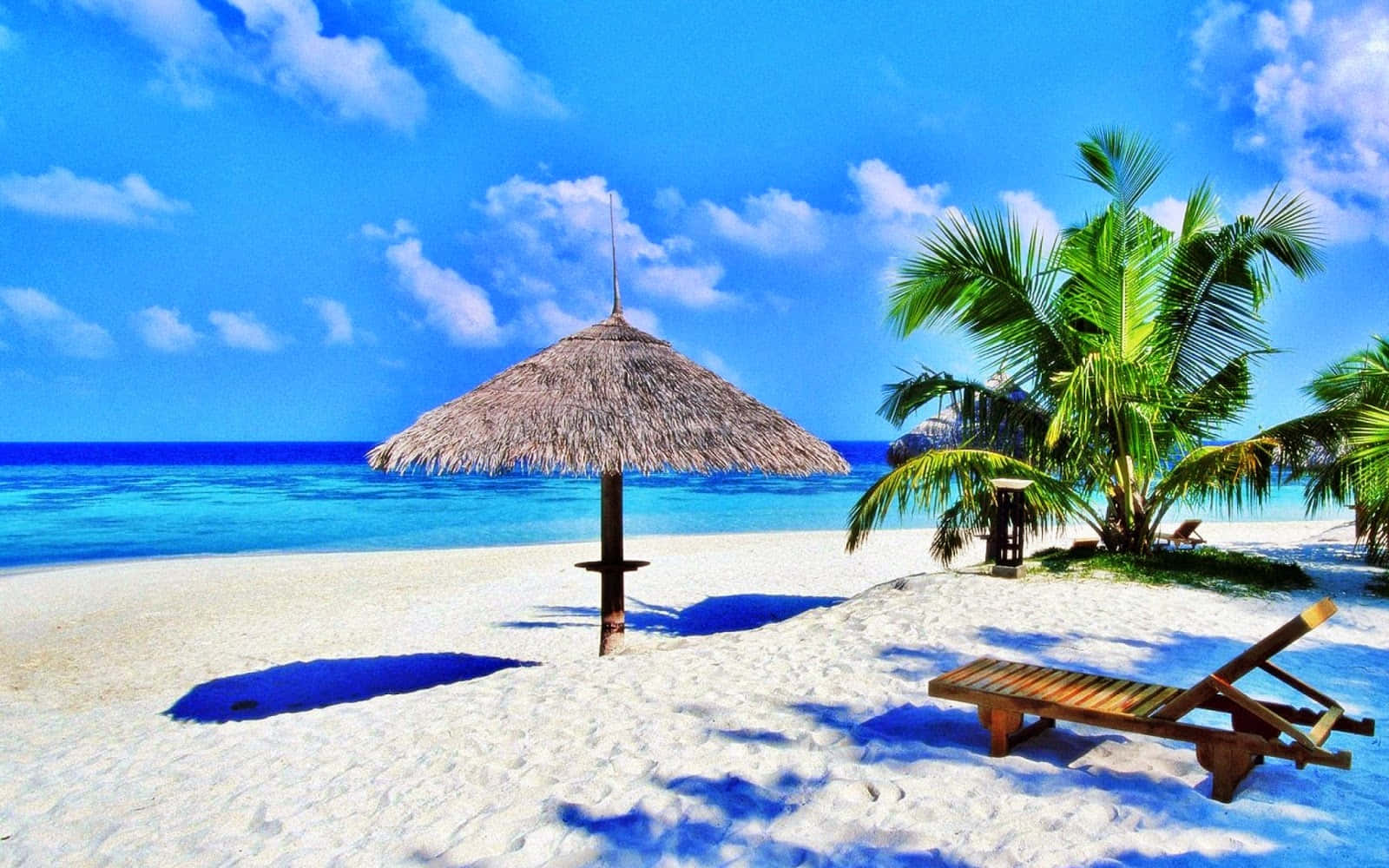 Vacation Mode 桌布 壁紙 — 充滿活力的熱帶海灘場景，白色沙灘上有茅草遮陽傘和躺椅，旁邊是碧綠的海水和棕櫚樹，頭頂是明亮的藍天。