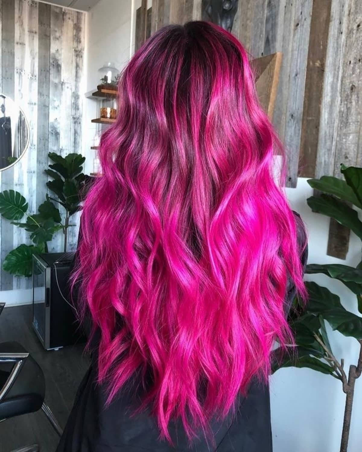 Magenta 桌布 壁紙 — 充滿活力的熱粉紅色波浪形頭髮在現代沙龍中沿著一個人的背部傾瀉而下，沙龍有木牆和綠色植物。