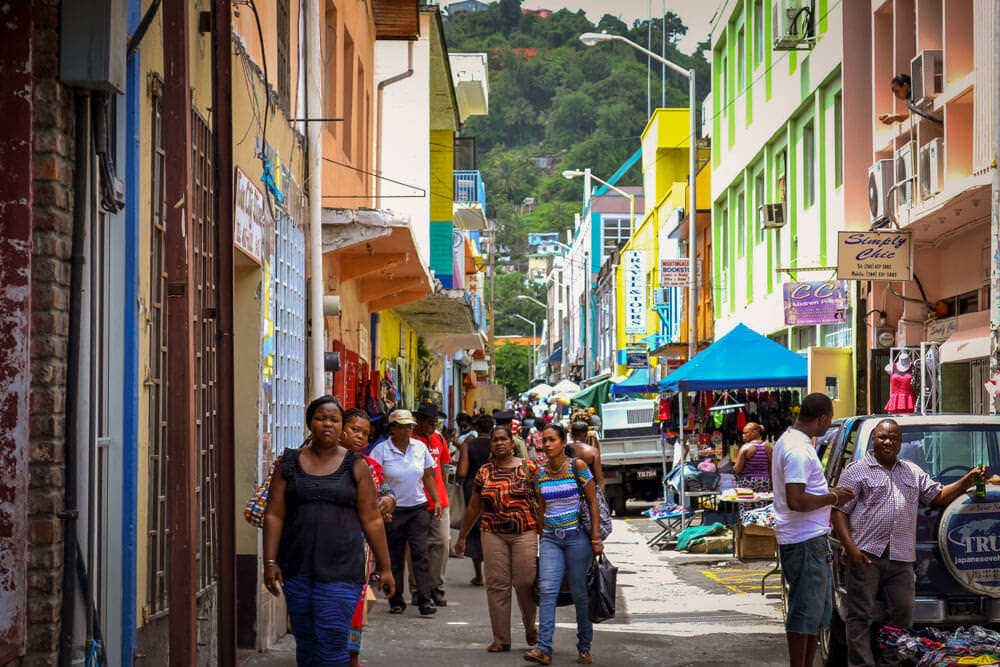 St Vincent And The Grenadines 桌布 壁紙 — 充滿活力的熱鬧街市，色彩繽紛的建築物和行人在明亮的日光下。
