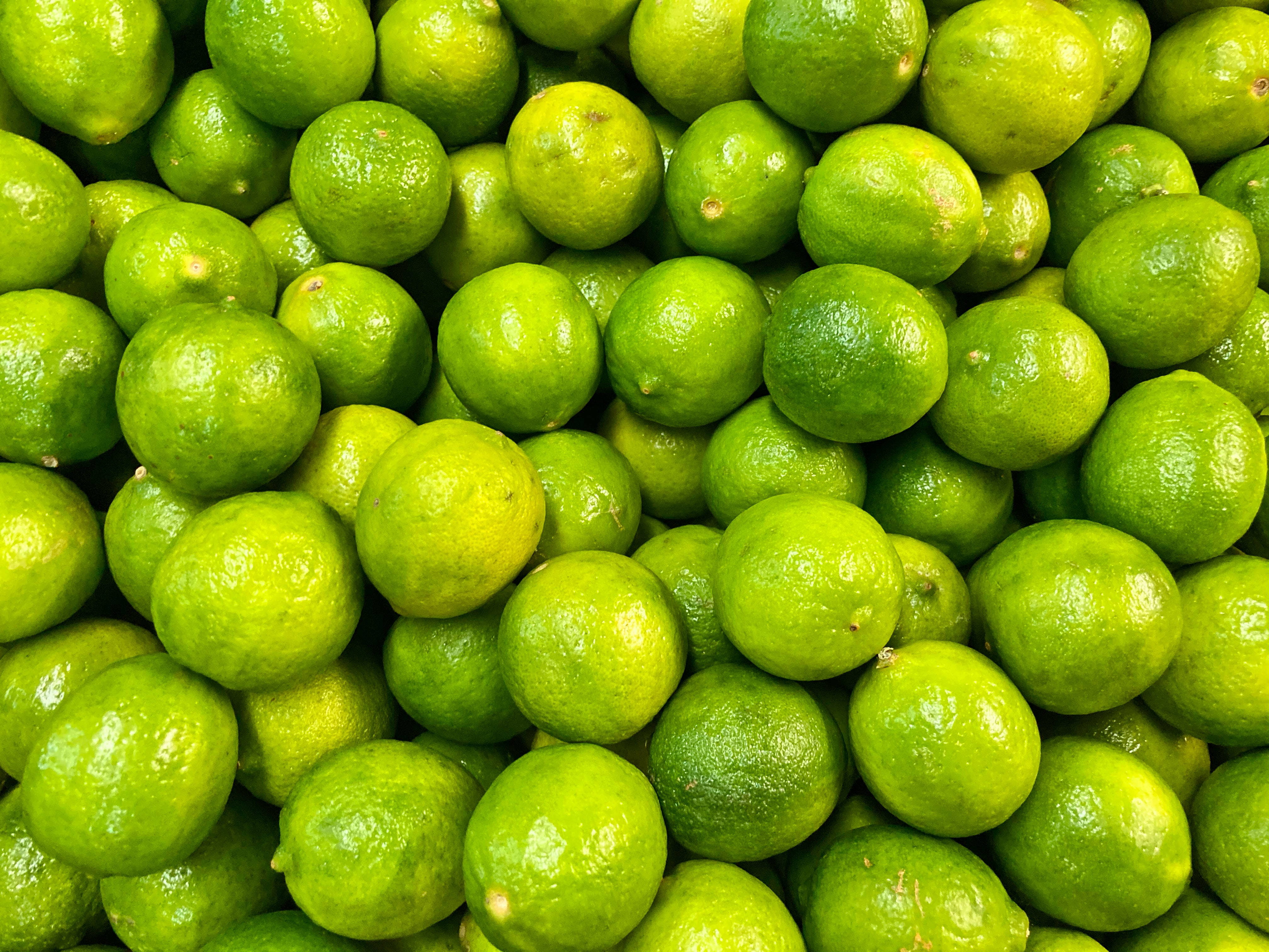 Fruits 桌布 壁紙 — 充滿活力的特寫，新鮮的綠色萊姆堆疊在一起，帶有光澤的果皮和自然瑕疵。