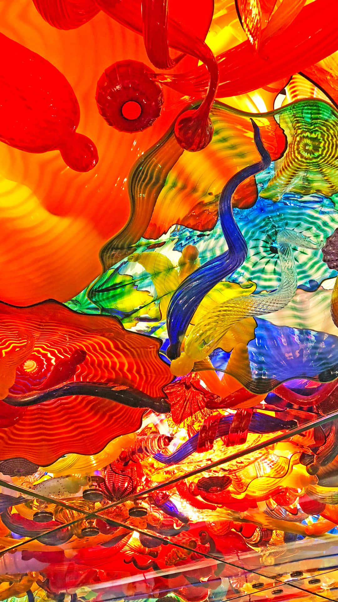 藝術 桌布 壁紙 — 充滿活力的玻璃雕塑，以火紅、藍色和黃色在頭頂動態旋轉，創造出令人眼花繚亂的天花板裝置。