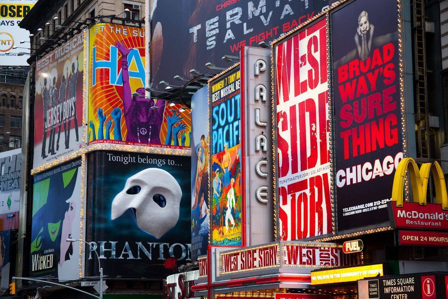 Broadway 桌布 壁紙 — 充滿活力的百老匯劇院廣告牌以耀眼的霓虹燈和色彩繽紛的音樂劇海報照亮時代廣場。