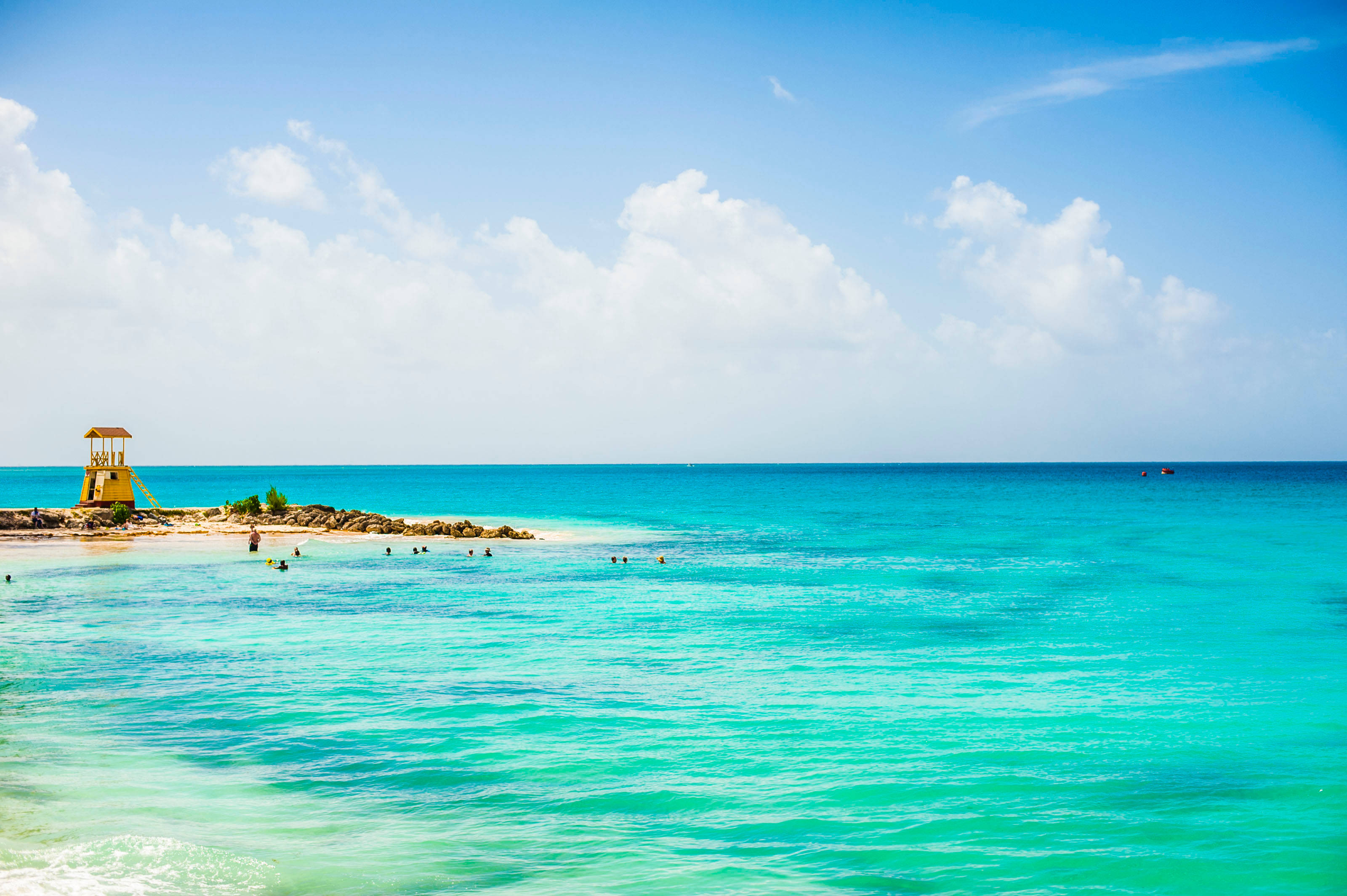 Barbados 桌布 壁紙 — 充滿活力的碧綠海水輕輕拍打沙灘，天空湛藍，點綴著蓬鬆的白雲。