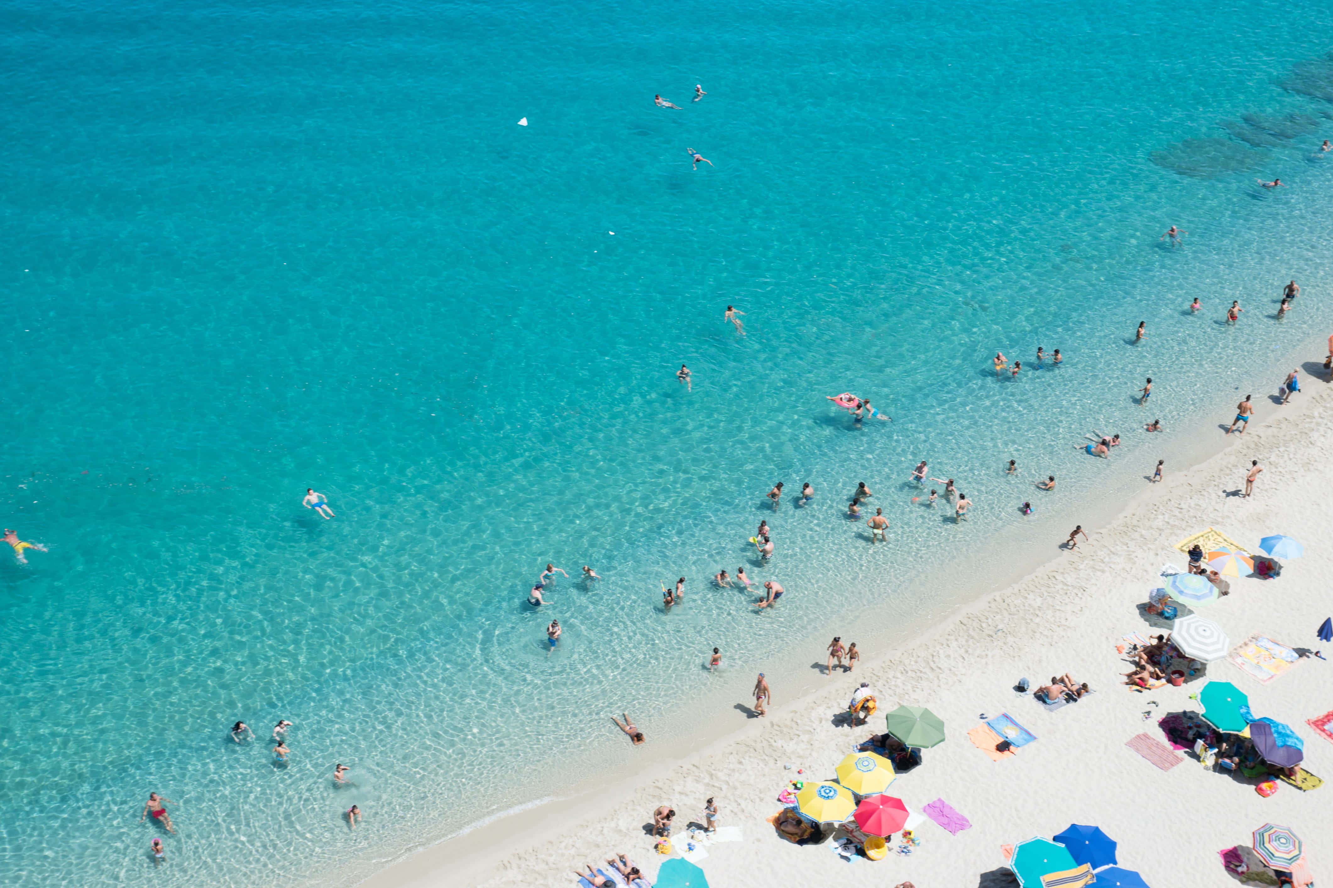 Italian Beach 桌布 壁紙 — 充滿活力的碧綠海灘鳥瞰圖，陽光普照，擠滿曬太陽和游泳的人們。