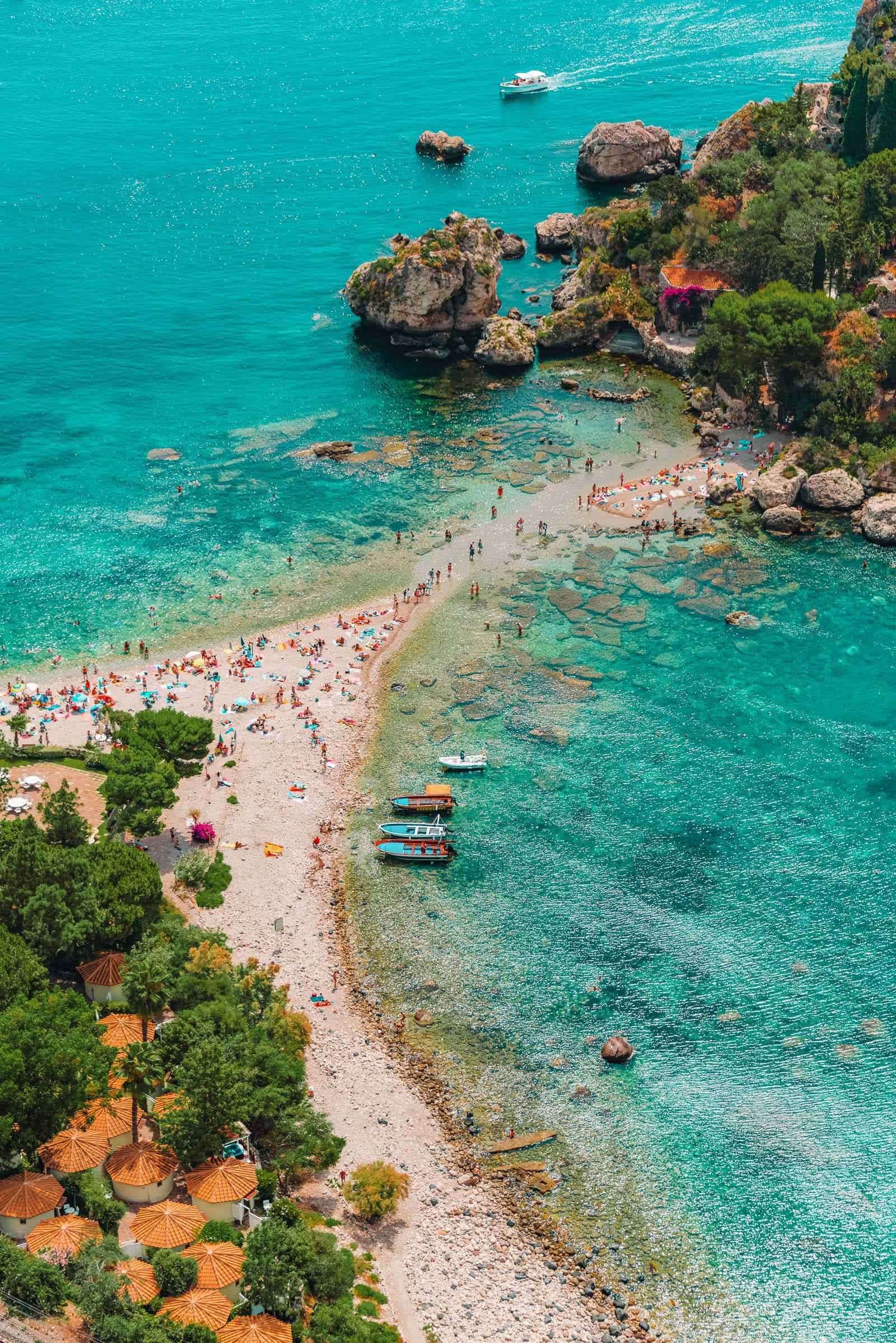 Italian Beach 桌布 壁紙 — 充滿活力的碧綠海灣鳥瞰圖，沙灘上擠滿了享受日光浴的人們，色彩繽紛的船隻停泊在岩石峭壁附近。
