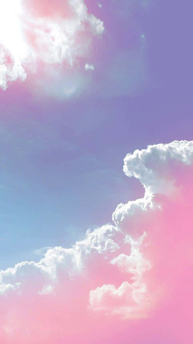 雲朵 桌布 壁紙 — 充滿活力的粉彩天空，蓬鬆的雲朵在柔和的藍色漸變中閃耀著粉紅色和紫色。