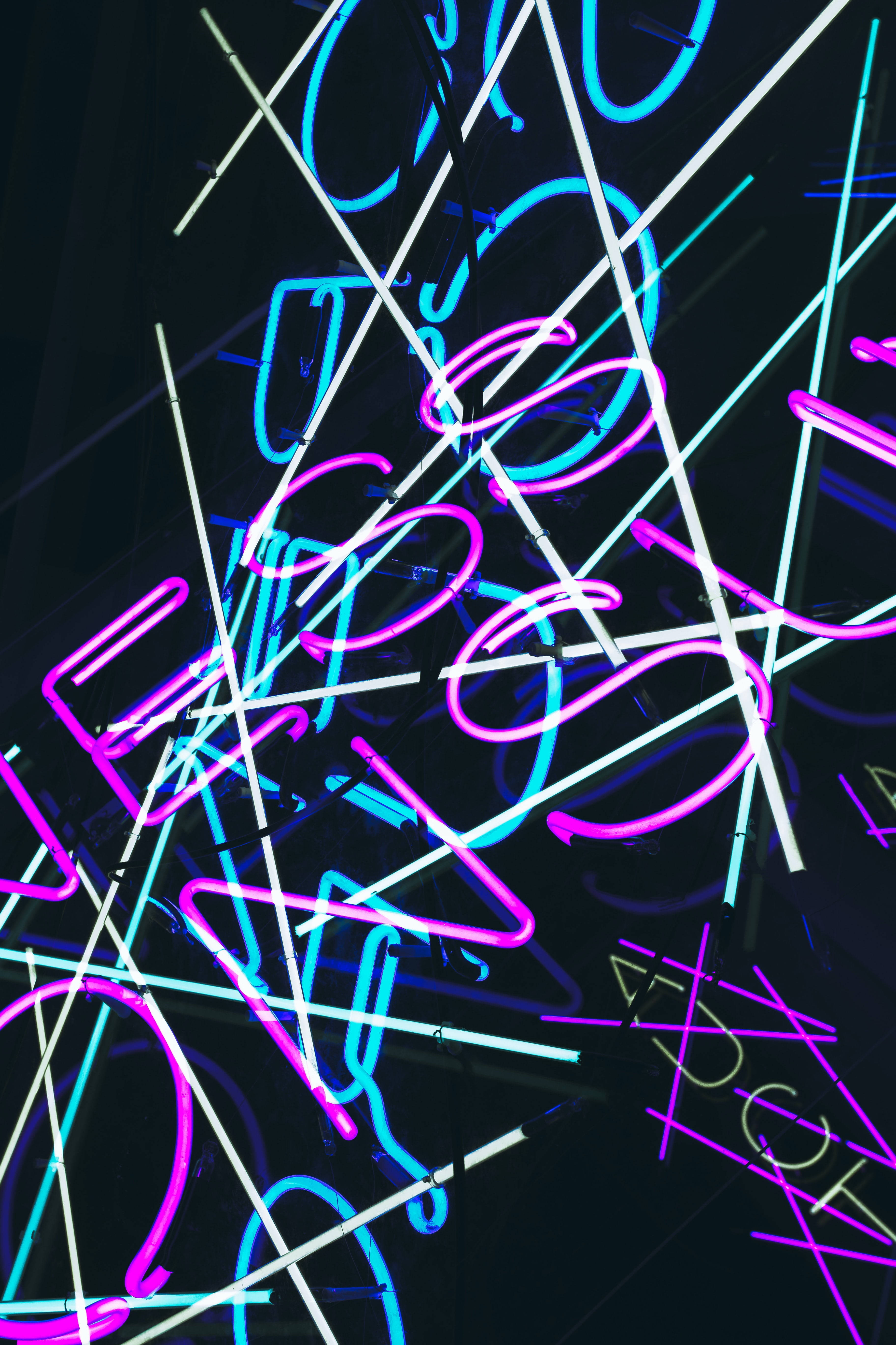 Dark Neon 桌布 壁紙 — 充滿活力的粉紅色、藍色和白色霓虹燈管在深色背景上交錯，形成動態發光的抽象圖案。