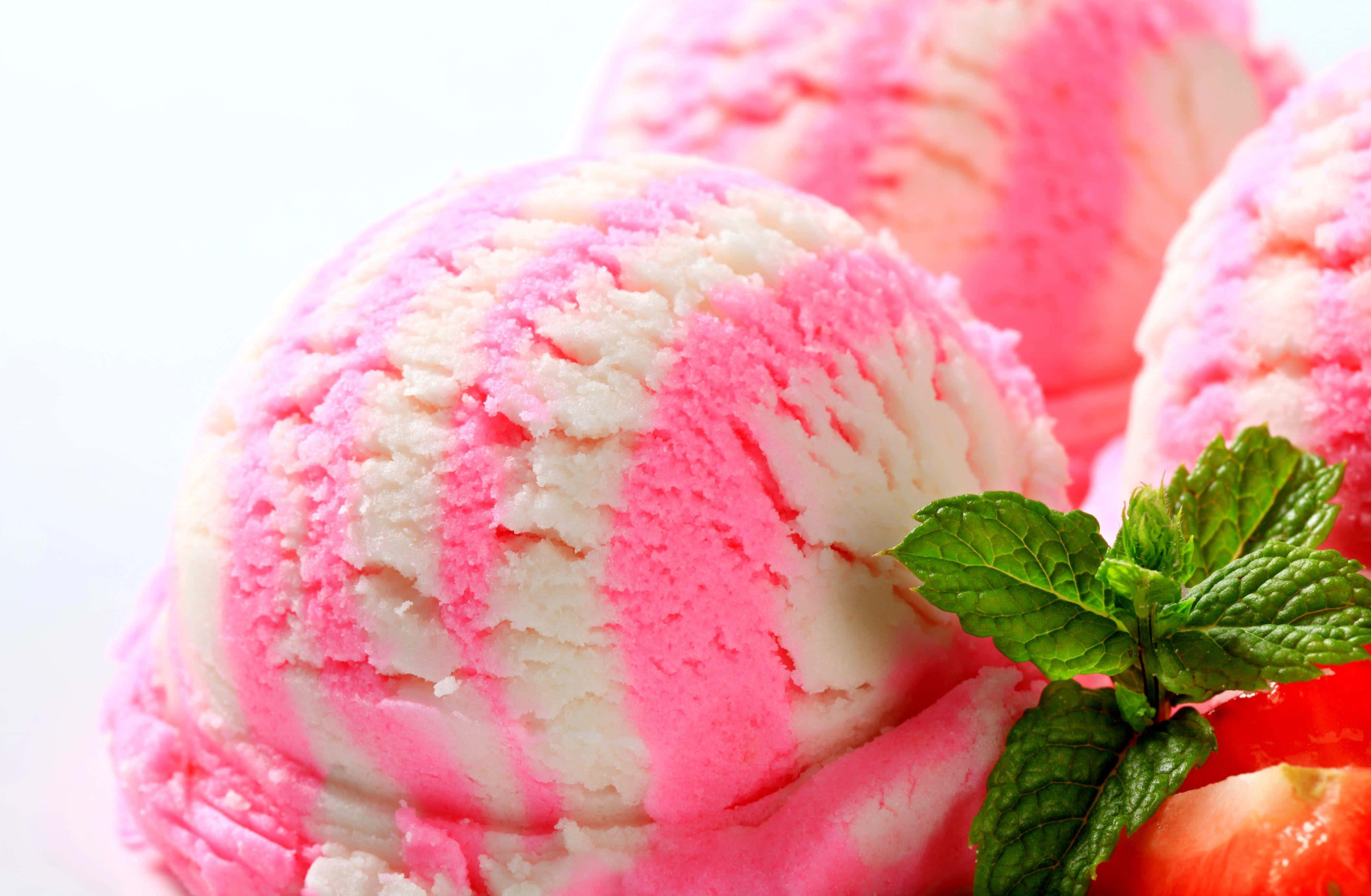 Ice Cream 桌布 壁紙 — 充滿活力的粉紅色和白色漩渦冰淇淋球的特寫，配上新鮮薄荷和草莓裝飾。