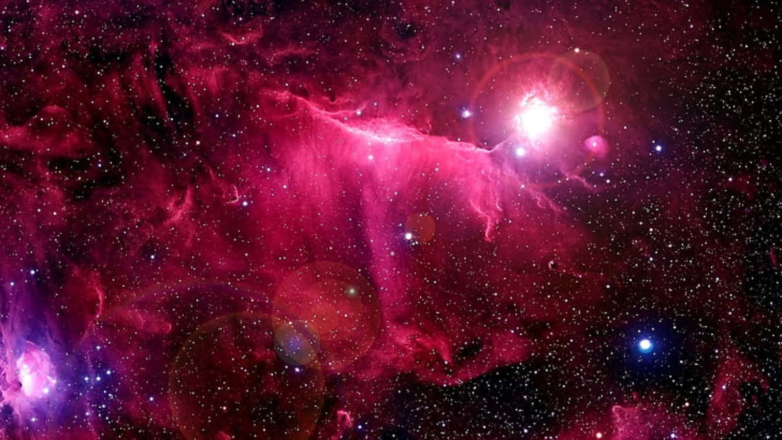 Celestial Bodies 桌布 壁紙 — 充滿活力的粉紅色和紫色宇宙星雲，在黑暗虛空中閃爍著散落的星星和鏡頭光暈。