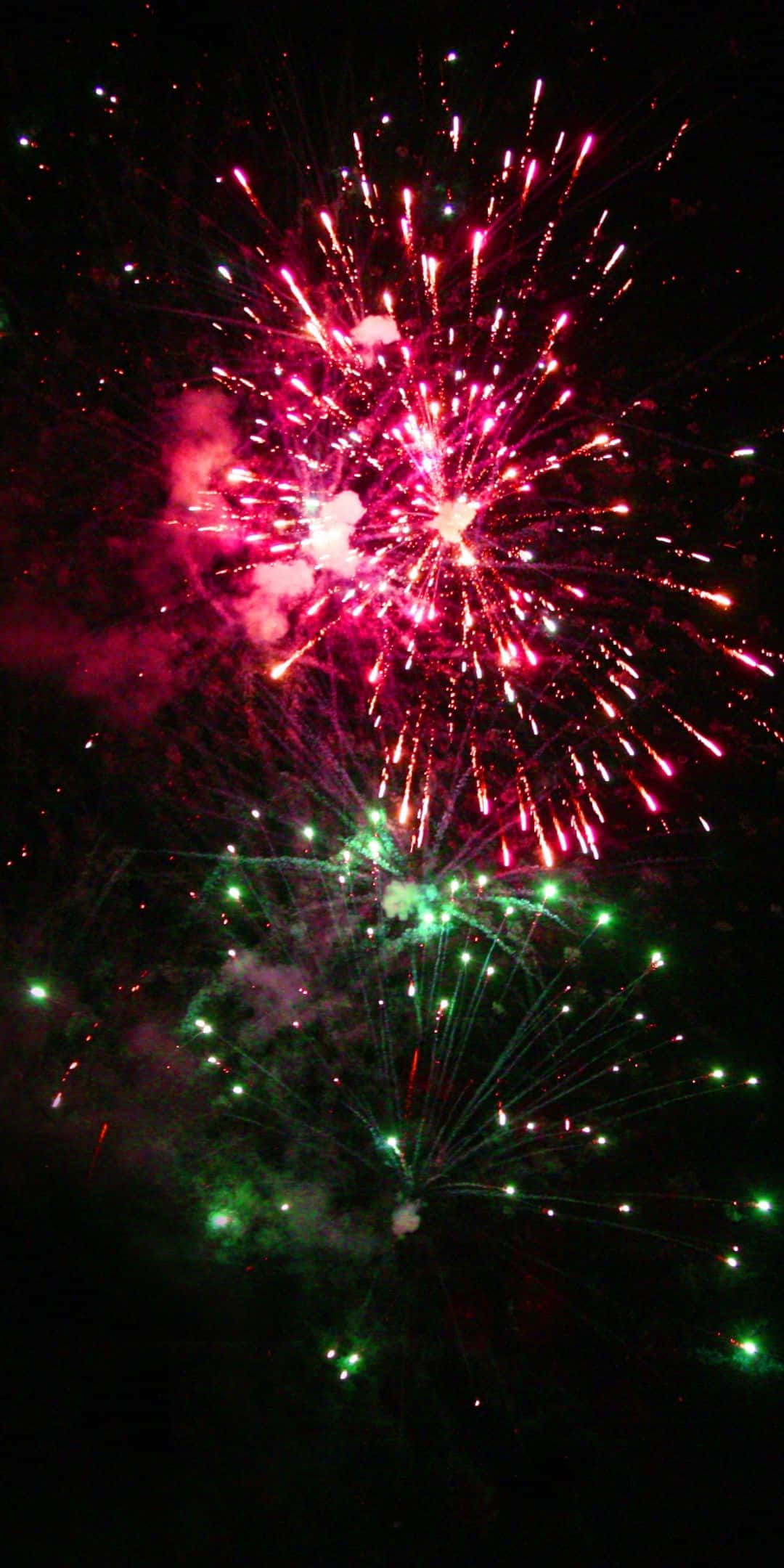firework 桌布 壁紙 — 充滿活力的粉紅色和綠色煙火在黑暗的夜空中綻放出耀眼的光芒。