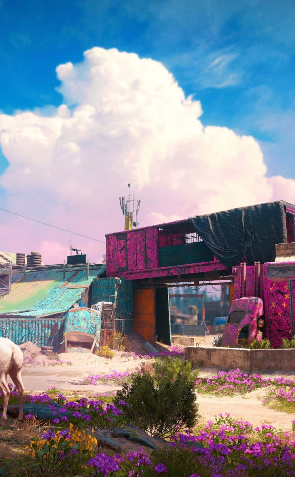 iPhone Xs Far Cry 4 桌布 壁紙 — 充滿活力的粉紅色和藍綠色塗鴉覆蓋的建築物從一個塵土飛揚的地塊中升起，該地塊盛開著紫色花朵，在明亮的藍天和蓬鬆的雲朵下。
