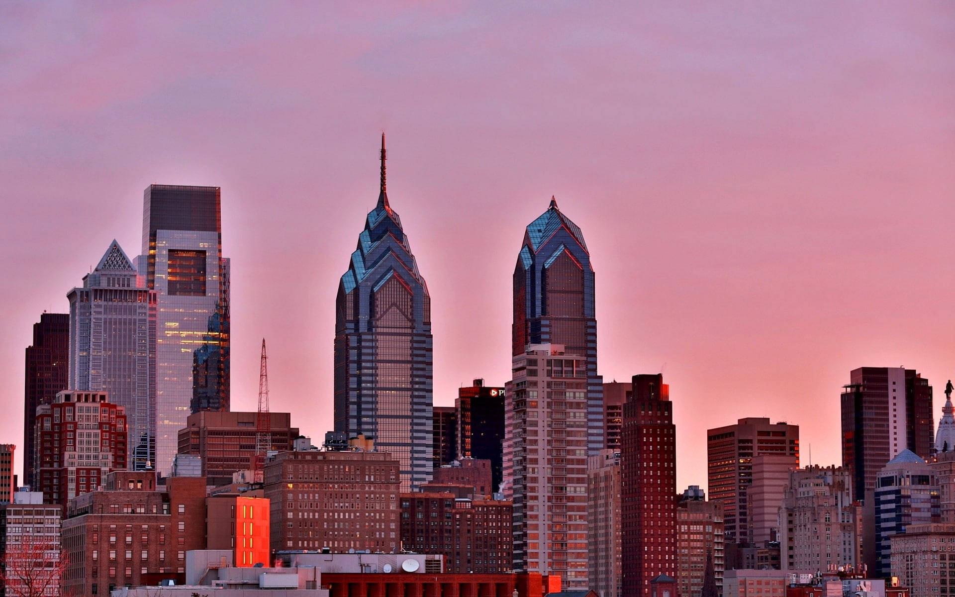 Philadelphia 桌布 壁紙 — 充滿活力的粉紅色夕陽以溫暖的色調沐浴費城天際線，摩天大樓刺穿暮色天空。
