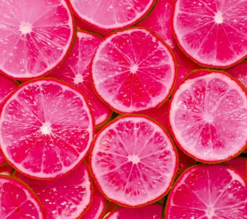 Pink Grapefruit 桌布 壁紙 — 充滿活力的粉紅色柑橘切片，排列成密集、多汁且色彩繽紛的圖案，果肉閃閃發光。