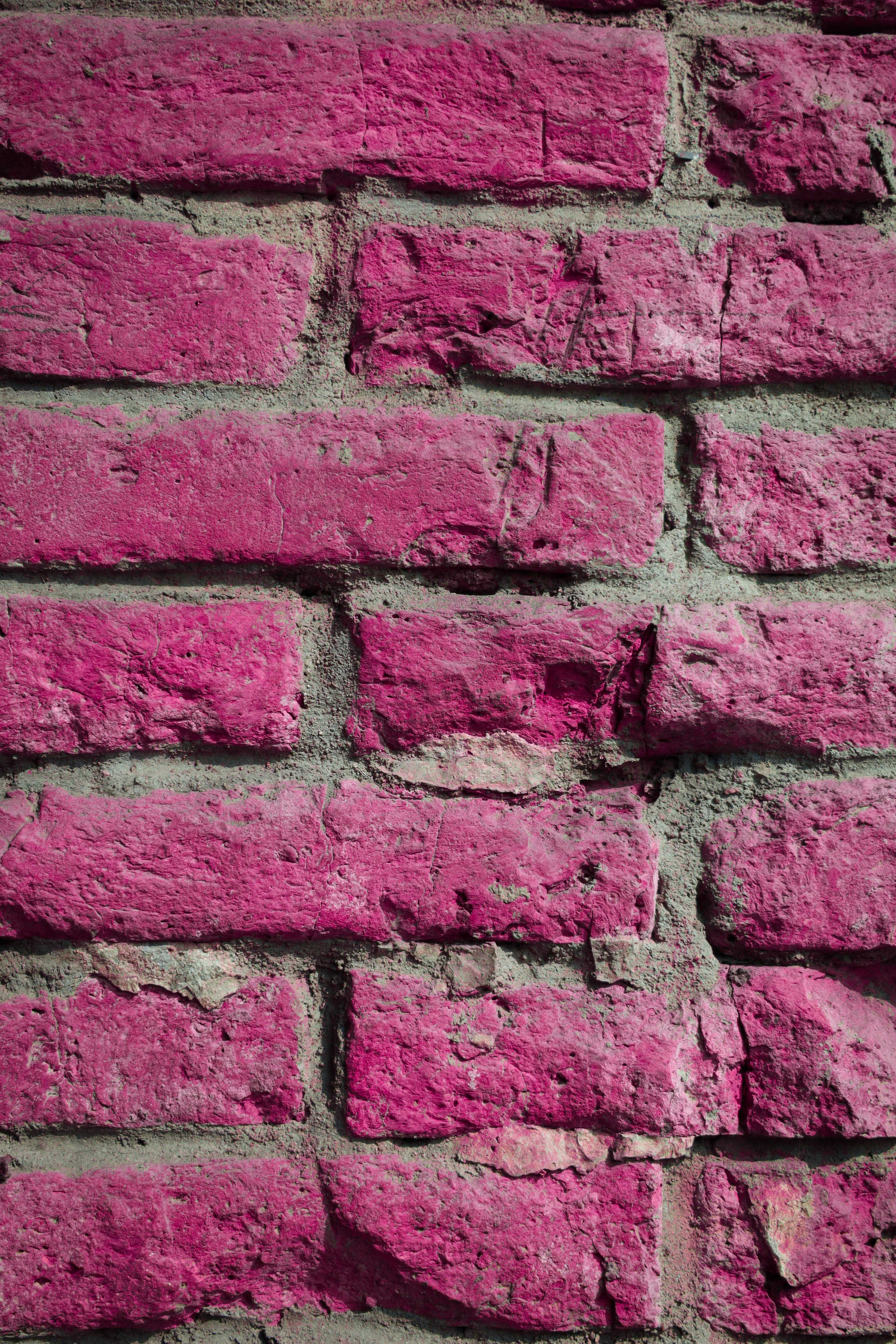 Pink Wall 桌布 壁紙 — 充滿活力的粉紅色磚塊帶有風化紋理和灰色砂漿，形成大膽的城市牆面圖案。