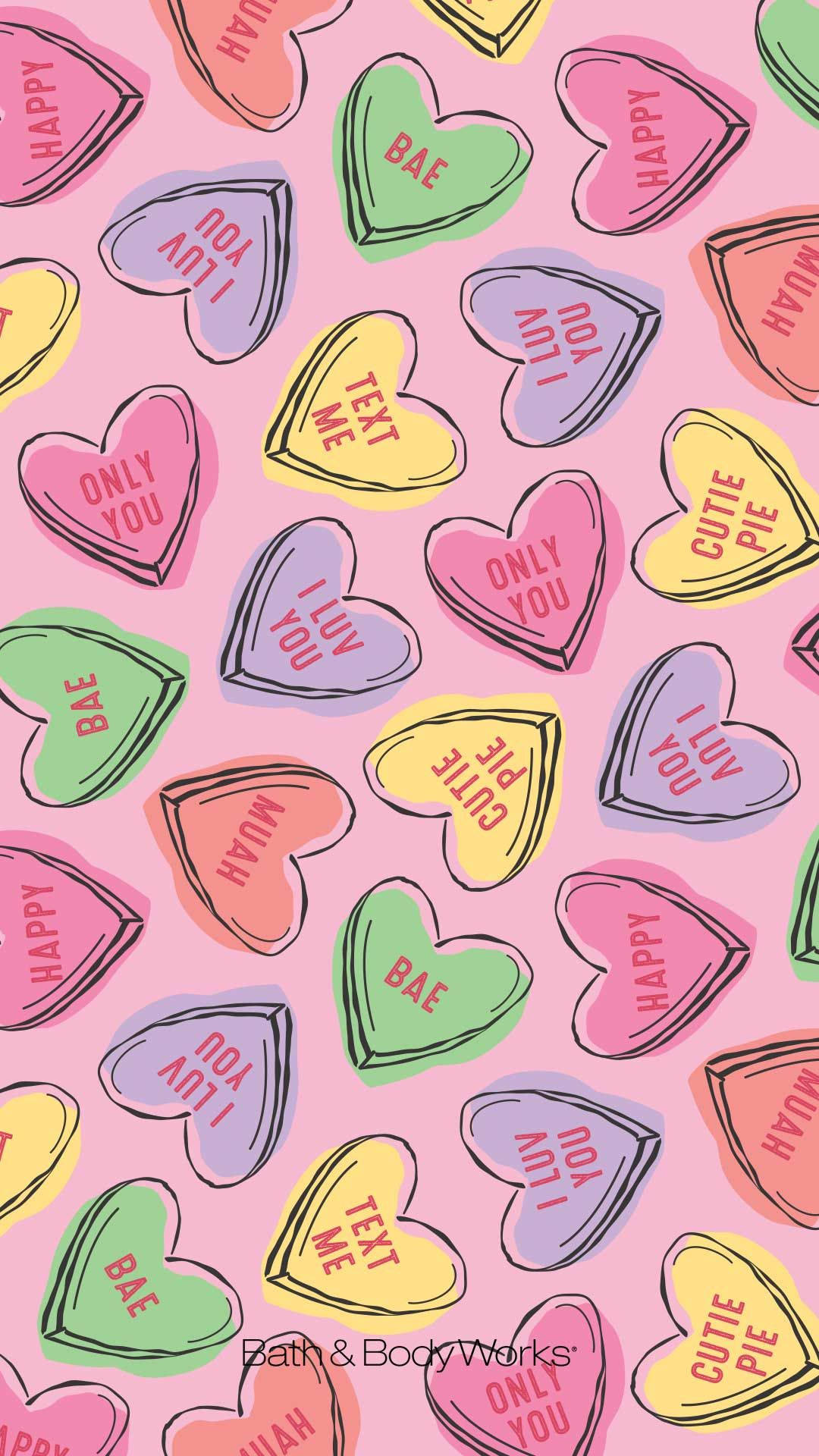 Valentines 桌布 壁紙 — 充滿活力的粉紅色背景，佈滿色彩繽紛的心形糖果，每顆糖果上都帶有俏皮手寫文字的甜蜜浪漫訊息。