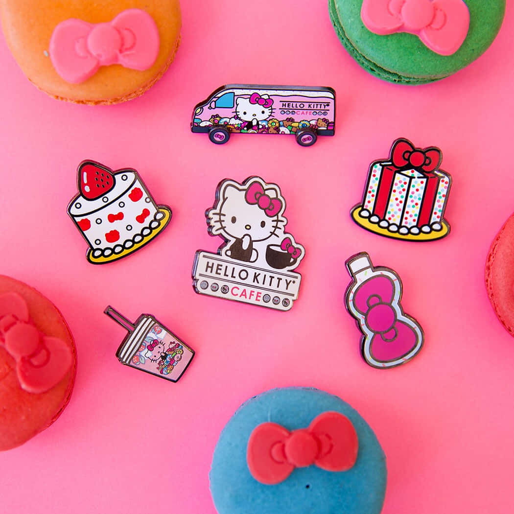 Hello Kitty 桌布 壁紙 — 充滿活力的粉紅色背景，帶有Hello Kitty主題的琺瑯別針和色彩繽紛的馬卡龍，以俏皮的平鋪方式排列。