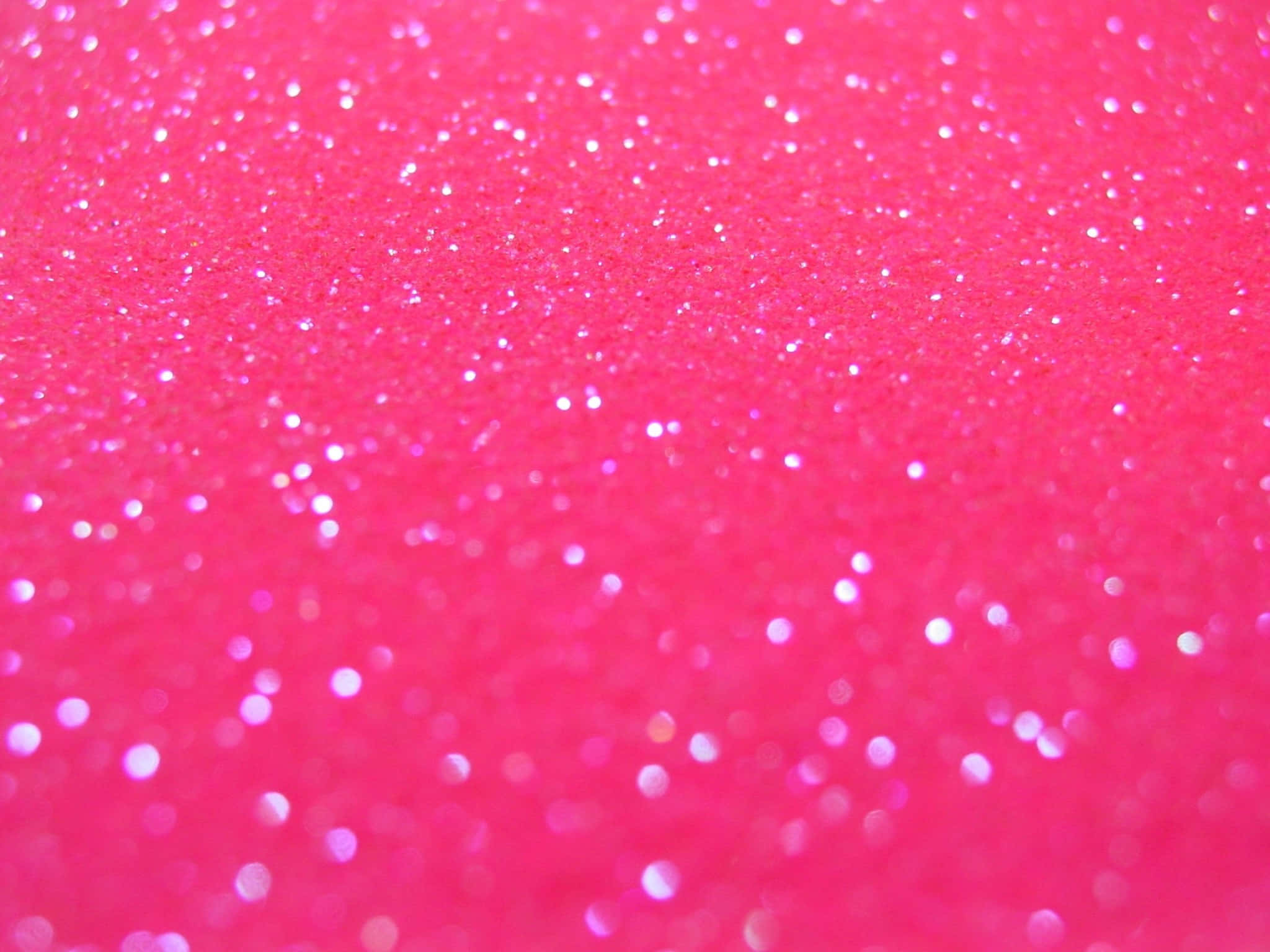 Pink Sparkles 桌布 壁紙 — 充滿活力的粉紅色閃粉特寫，帶有閃爍的白色顆粒，營造出閃閃發光的紋理表面。