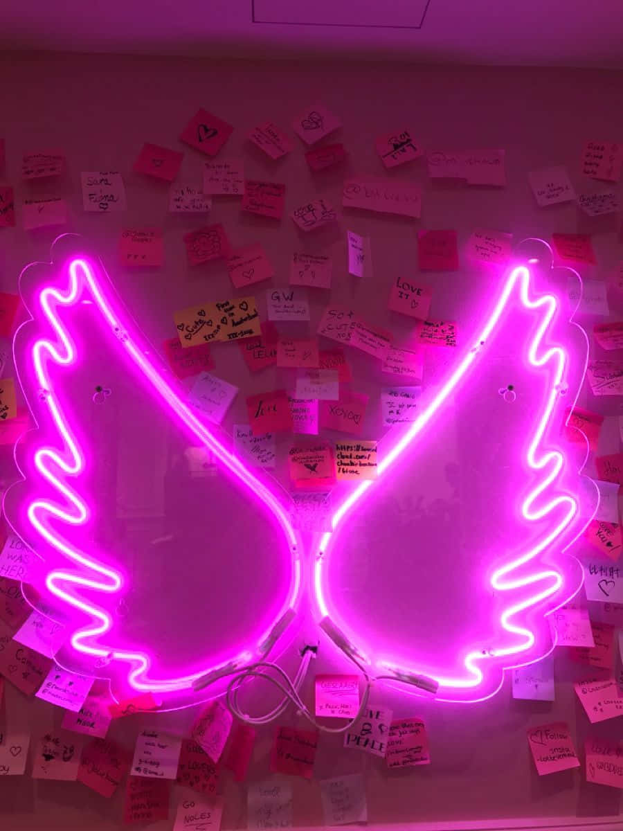 neon sign 桌布 壁紙 — 充滿活力的粉紅色霓虹天使翅膀在佈滿彩色手寫便利貼的牆上發光。
