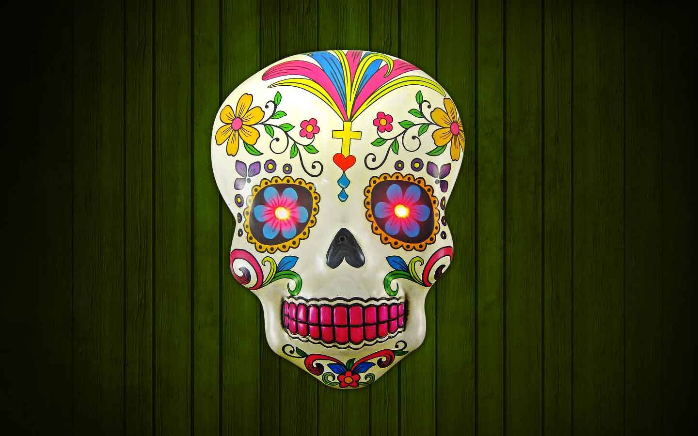 Dia De Los Muertos 桌布 壁紙 — 充滿活力的糖骷髏，帶有發光的花卉眼睛，安裝在深綠色木板上。