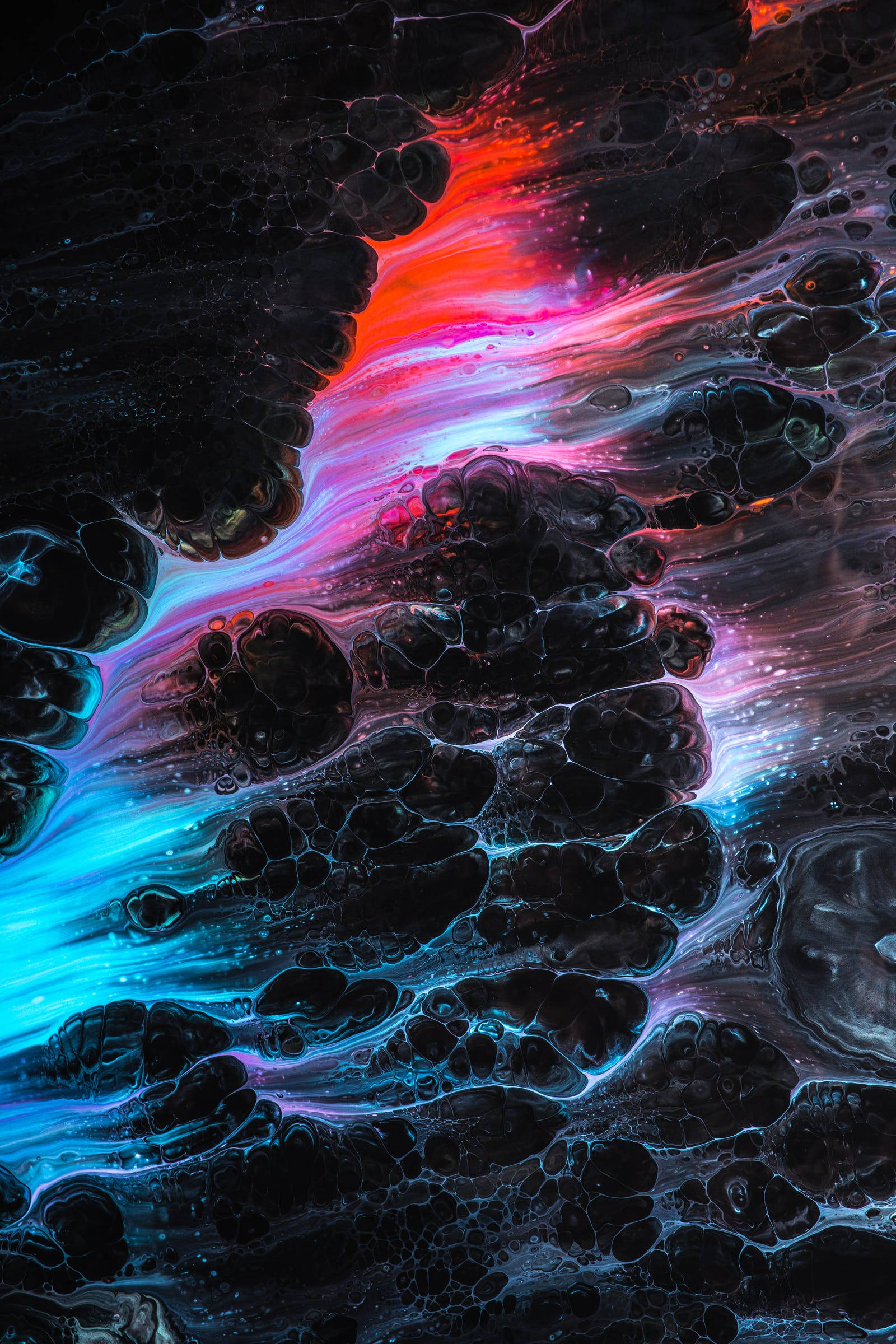 Neon Phone 桌布 壁紙 — 充滿活力的紅色、粉紅色和藍色霓虹燈宇宙漩渦，像超現實星雲一樣流過深色紋理液體。