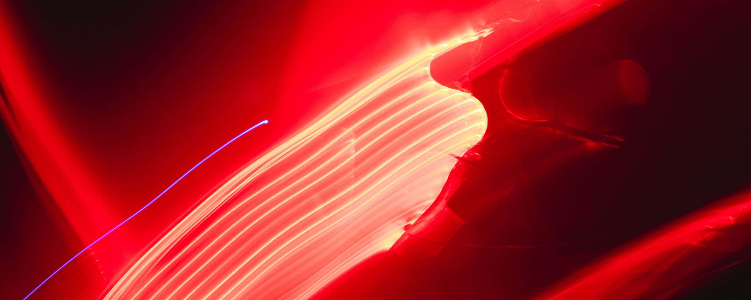 Neon Light 桌布 壁紙 — 充滿活力的紅色和橙色光跡在動態長時間曝光拍攝中劃過黑暗背景。
