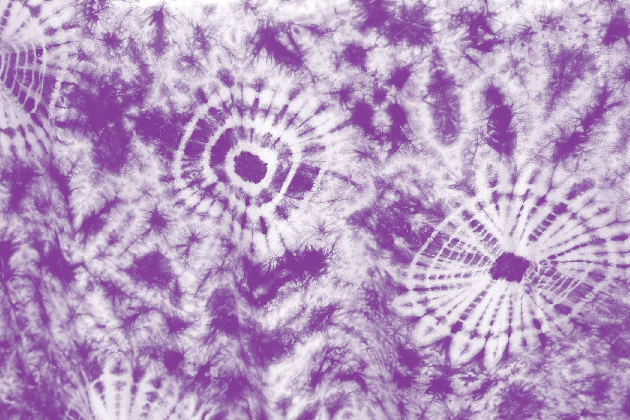 dye 桌布 壁紙 — 充滿活力的紫色和白色紮染布料，帶有複雜的螺旋和爆發圖案，營造出迷幻的抽象紋理。