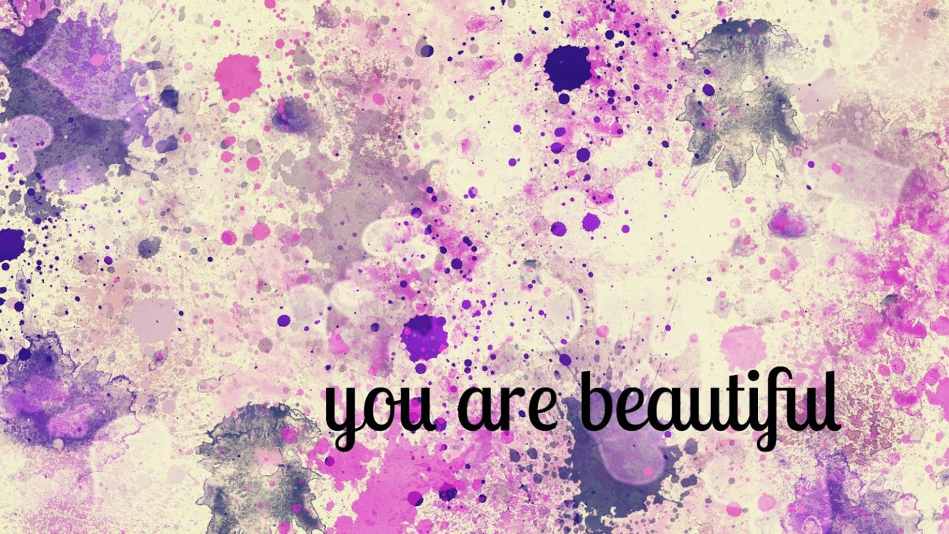You Are Beautiful 桌布 壁紙 — 充滿活力的紫色和粉紅色水彩潑濺形成夢幻般的抽象背景，並以優雅的黑色字體寫上「你很美麗」這句話。