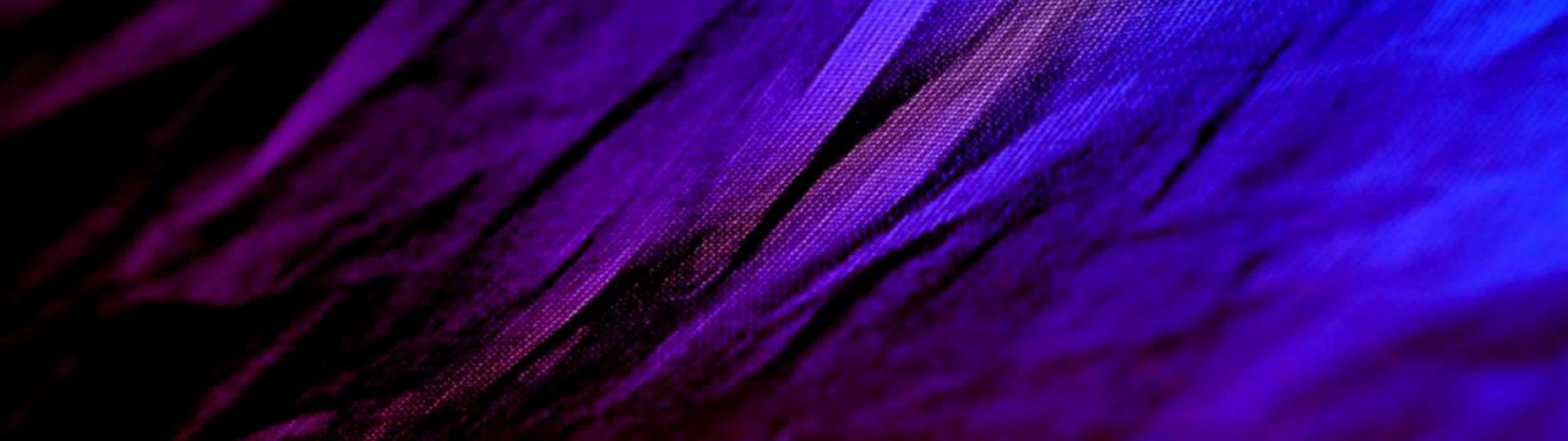 Purple Texture 桌布 壁紙 — 充滿活力的紫色和藍色抽象布料紋理，帶有對角線摺痕和深色陰影。