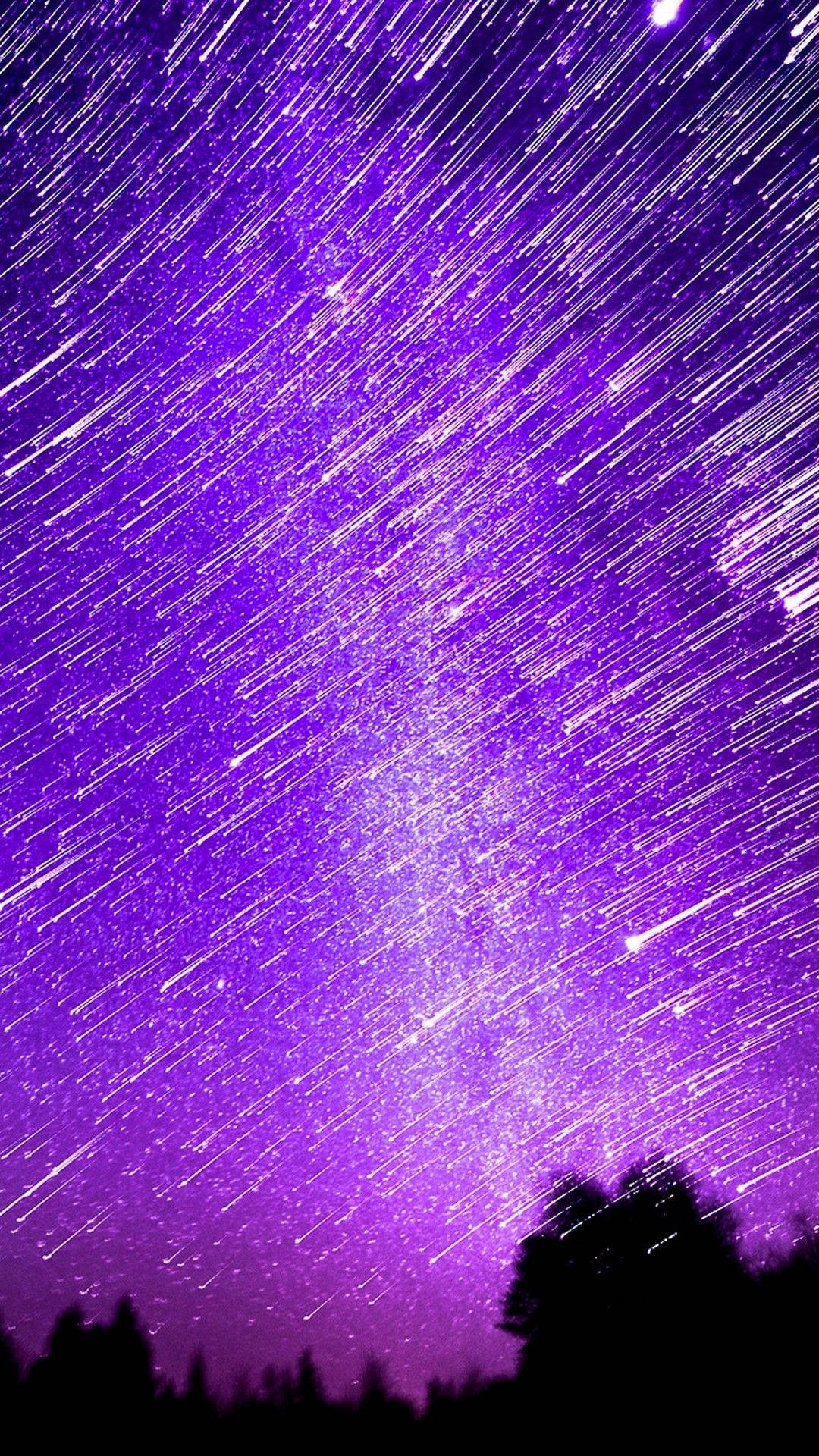美學 iPhone 壁紙 桌布 壁紙 — 充滿活力的紫色夜空，帶有星軌，拱在黑暗的樹木剪影之上。
