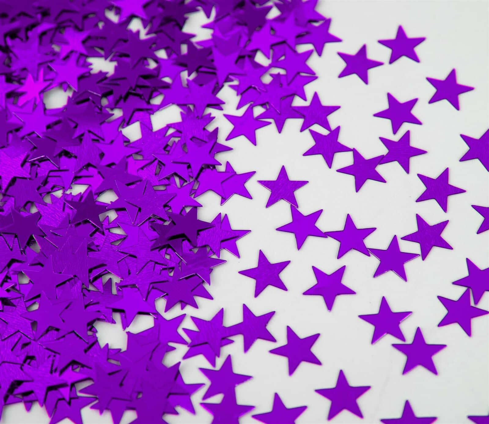 Purple Star 桌布 壁紙 — 充滿活力的紫色星形五彩紙屑散落在潔白的表面上，營造出節日喜慶的質感。