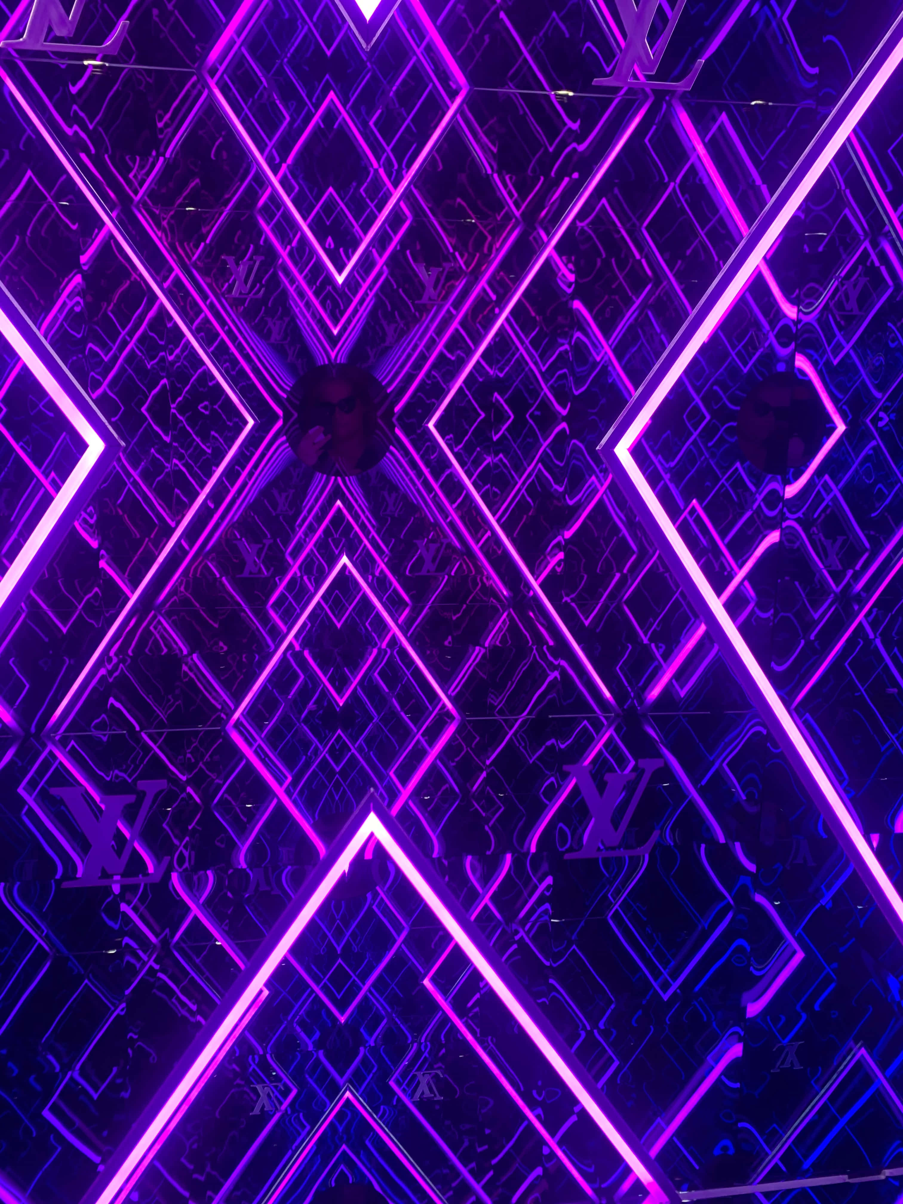 Purple Neon 桌布 壁紙 — 充滿活力的紫色霓虹燈在鏡面牆上形成幾何圖案，營造出令人眼花撩亂的未來感隧道效果。