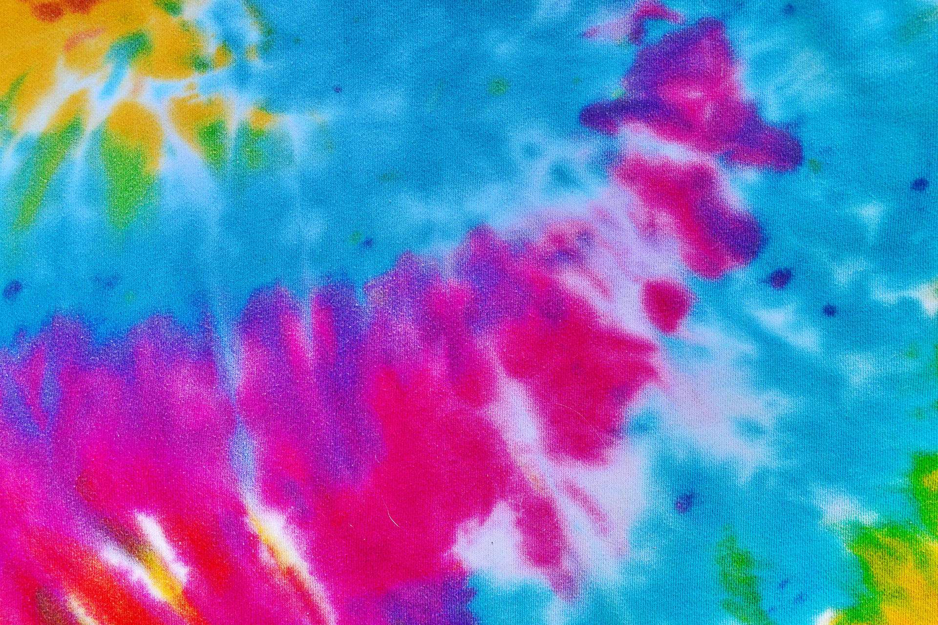 dye 桌布 壁紙 — 充滿活力的紮染布料，呈現電光粉紅、藍、黃、綠色，並帶有白色亮點。
