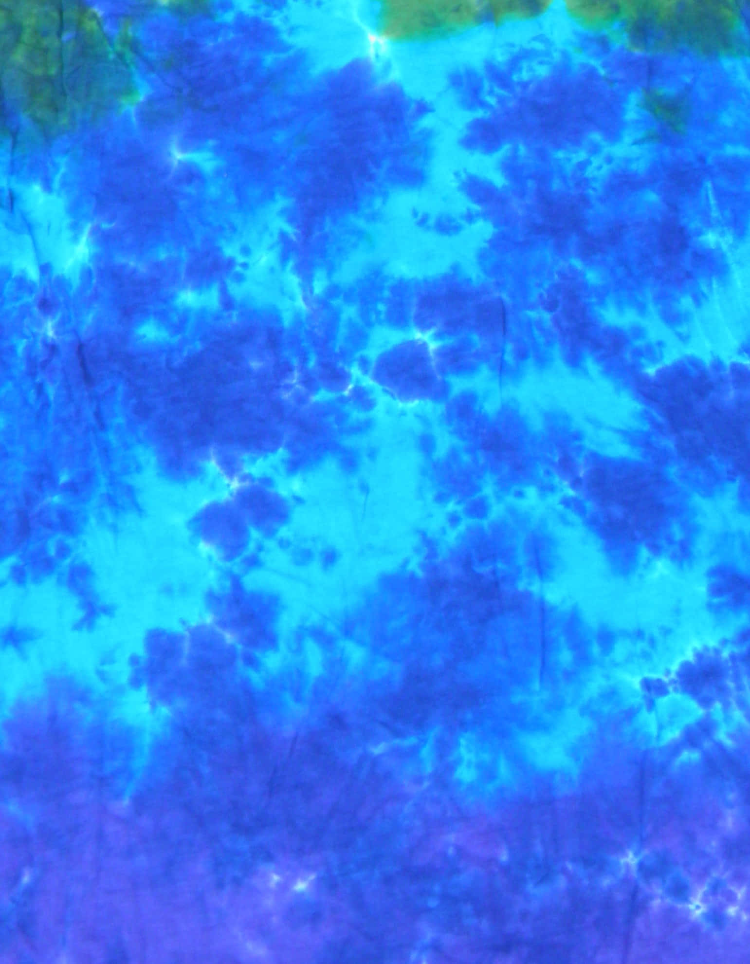 Blue Tie Dye 桌布 壁紙 — 充滿活力的紮染布料，呈現電光藍和紫色漩渦，帶有微妙的綠色點綴和紋理布線。