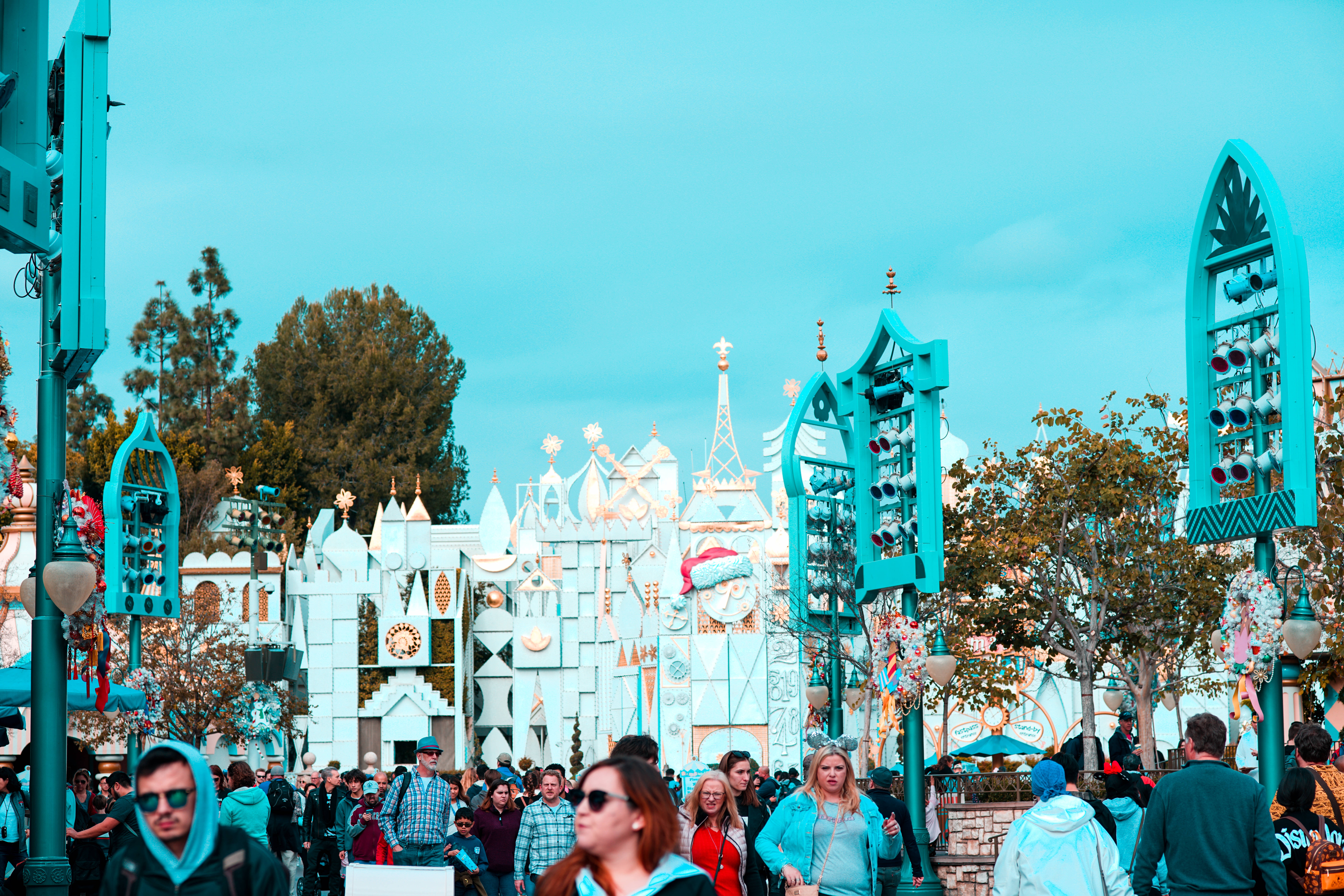 Disneyland Desktop 桌布 壁紙 — 充滿活力的綠松石和白色幻想建築在晴朗的藍天下聳立在熙熙攘攘的人群之上。