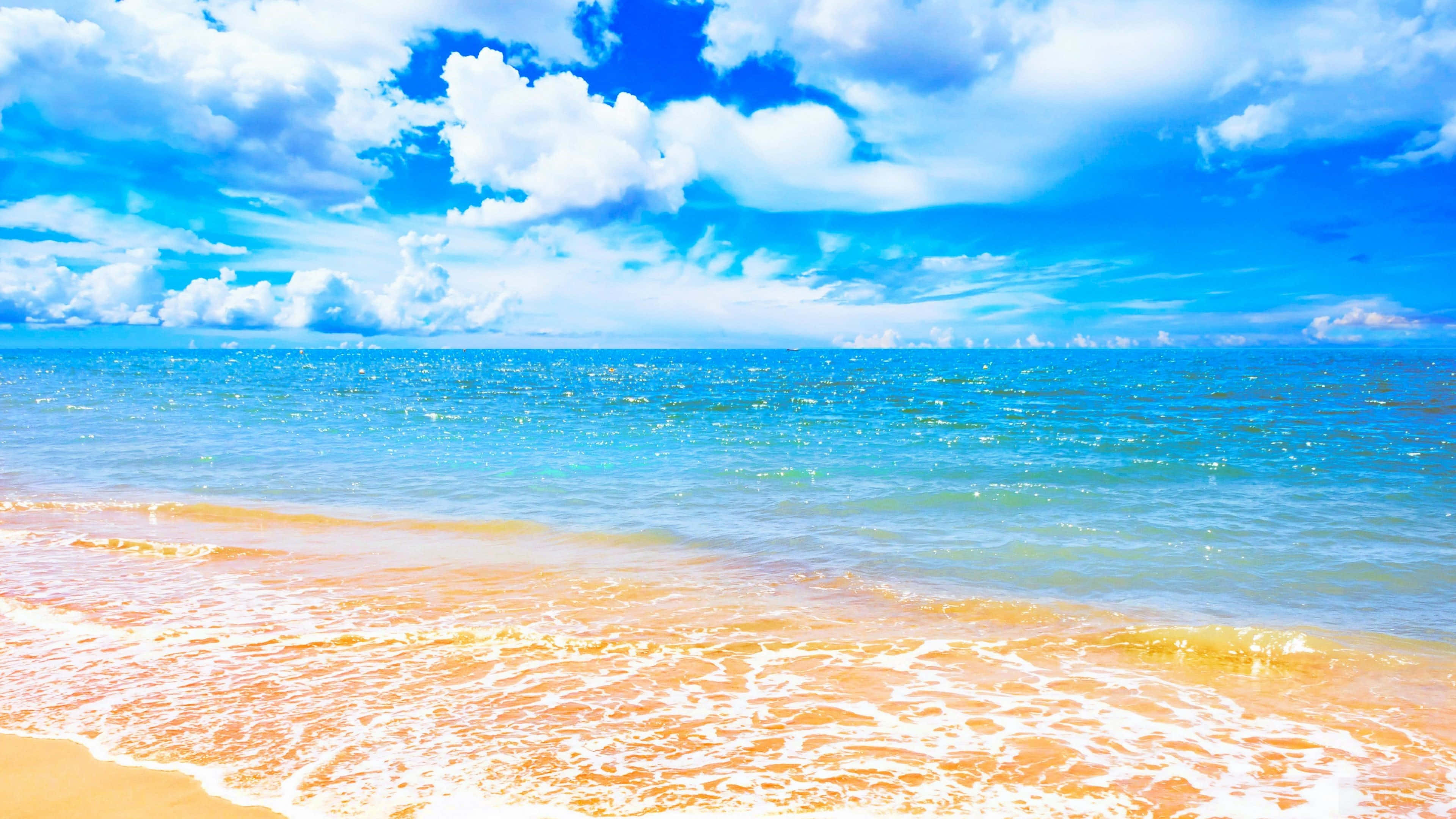 夏天 桌布 壁紙 — 充滿活力的綠松石色海浪拍打著金色沙灘，上方是佈滿蓬鬆白雲的明亮藍天。