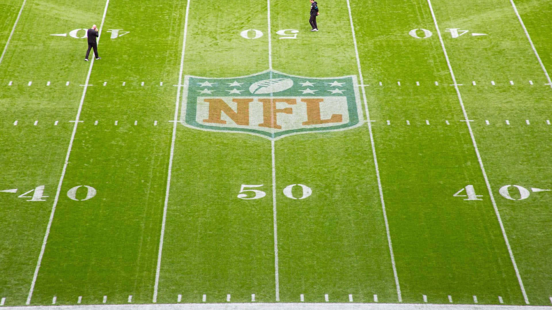 NFL 桌布 壁紙 — 充滿活力的綠色NFL足球場的鳥瞰圖，帶有白色碼線，兩人在50碼線附近站立。