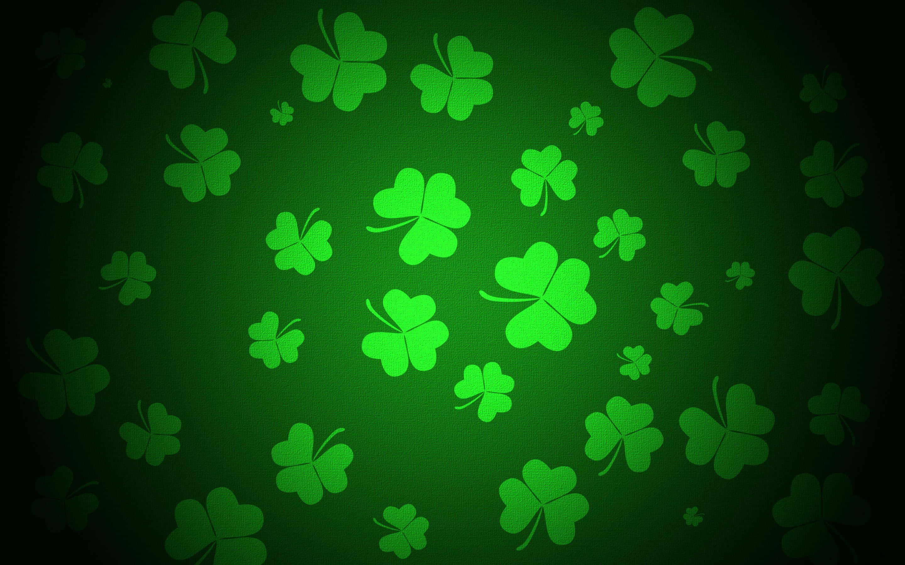 Saint Patricks Day 桌布 壁紙 — 充滿活力的綠色三葉草在深色漸變背景上發光，形成節日圖案。