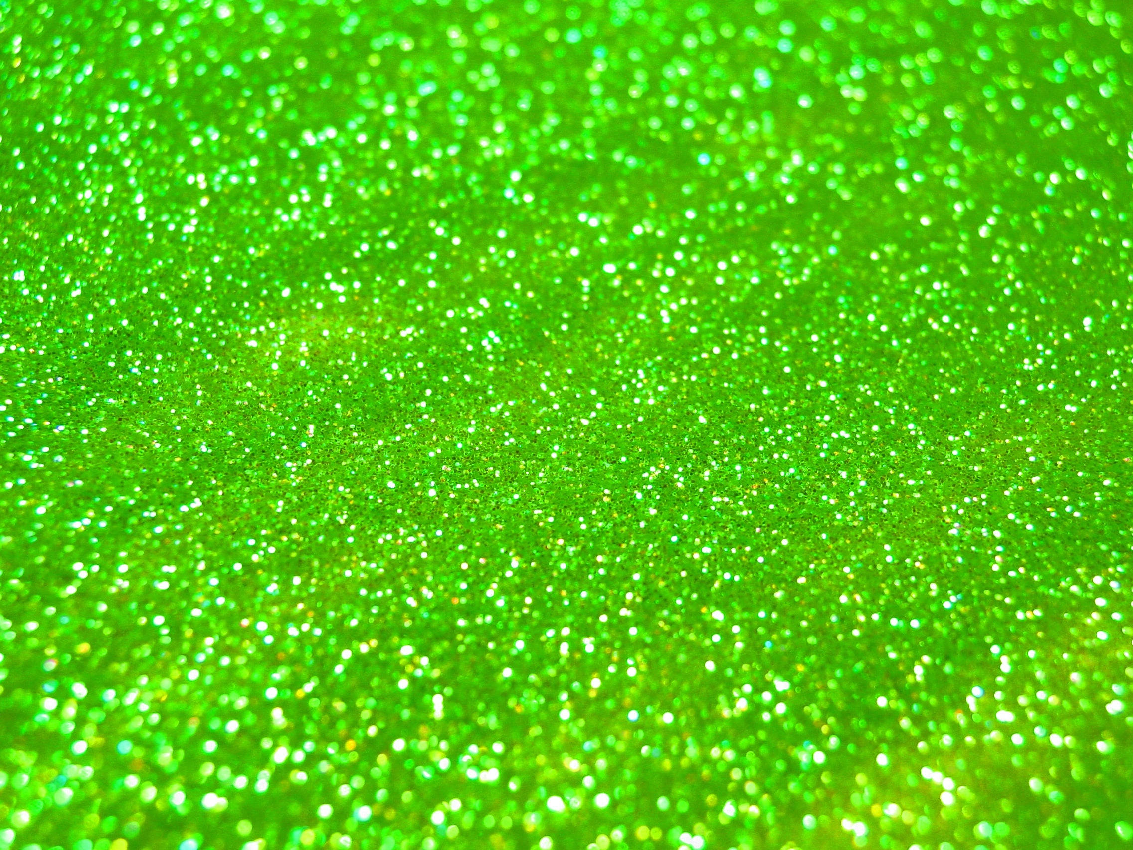 Green Glitter 桌布 壁紙 — 充滿活力的綠色亮粉特寫，整個畫面中閃爍的顆粒捕捉光線。