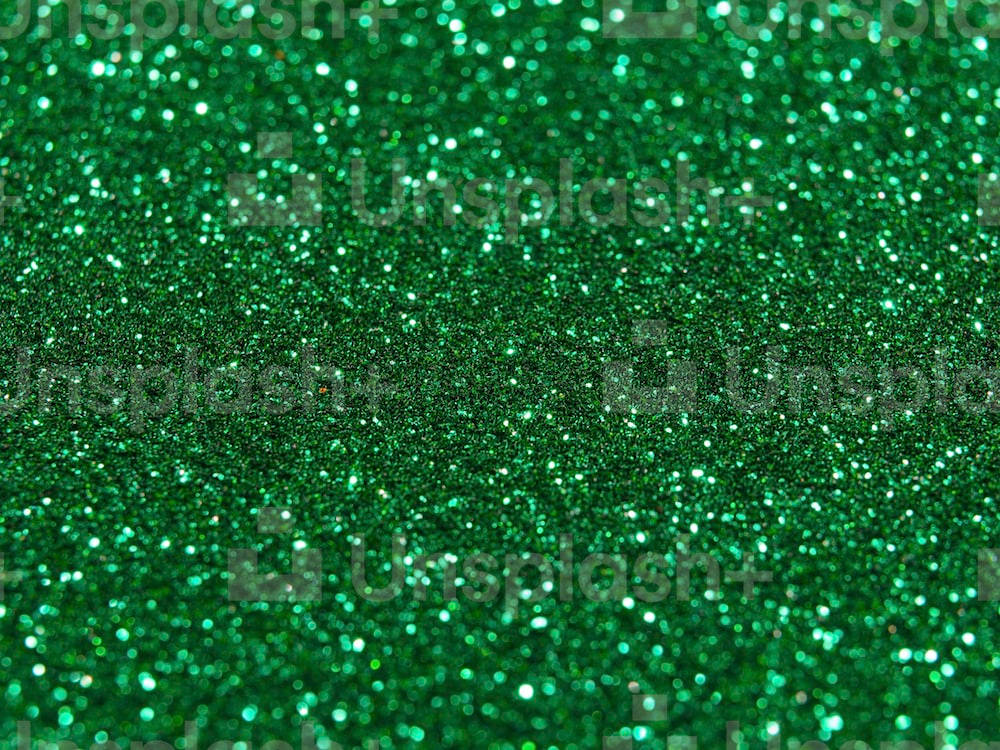 Green Glitter 桌布 壁紙 — 充滿活力的綠色亮粉特寫，閃爍的顆粒在光線下形成密集的紋理圖案。